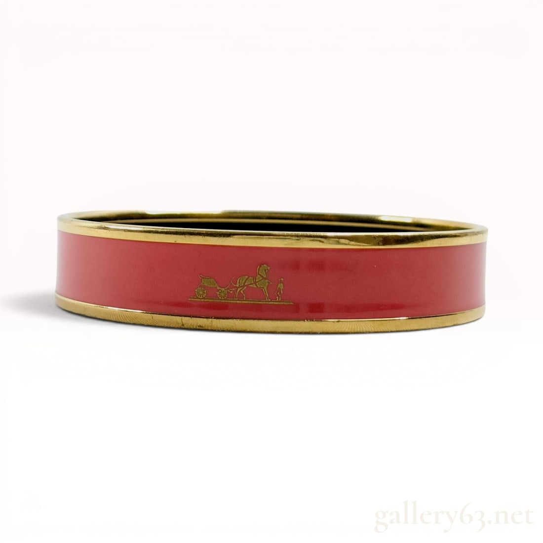 Hermes Caleche Red Enamel and Gold-Plated Narrow Bangle Bracelet: Hermes Caleche narrow bangle bracelet. The exterior features a red enamel inlay decorated with a repeating gold-tone horse and carriage motif, which is a signature design of the house. The enamel band