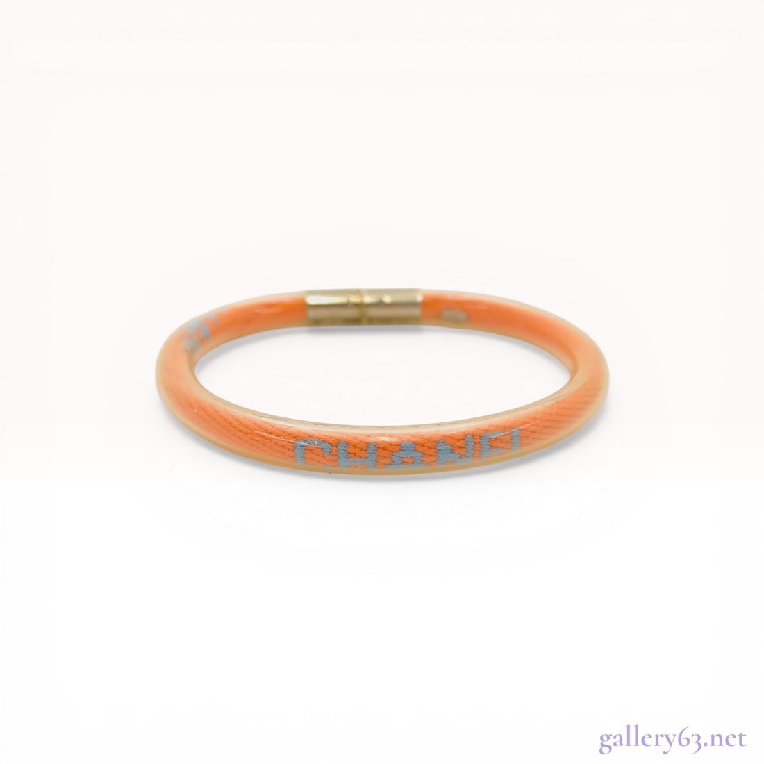 Chanel Spring 2000 Orange Vinyl Tube Bangle Bracelet: Chanel vinyl tube bangle bracelet from the Spring 2000 collection. The piece features an orange corded interior encased in a clear resin shell with light blue Chanel lettering and a gold-tone metal ba