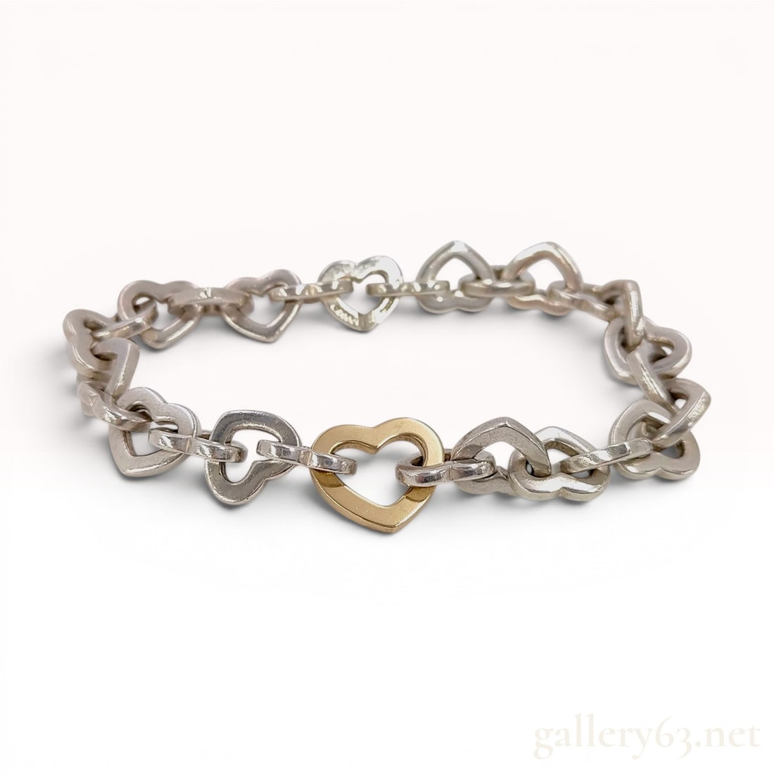 Tiffany & Co. 18K Gold & Sterling SilverHeart Link Bracelet: This authentic Tiffany & Co. heart link bracelet features a chain of interlocking open-heart motifs. The piece is crafted in two-tone precious metals, consisting primarily of sterling silver links