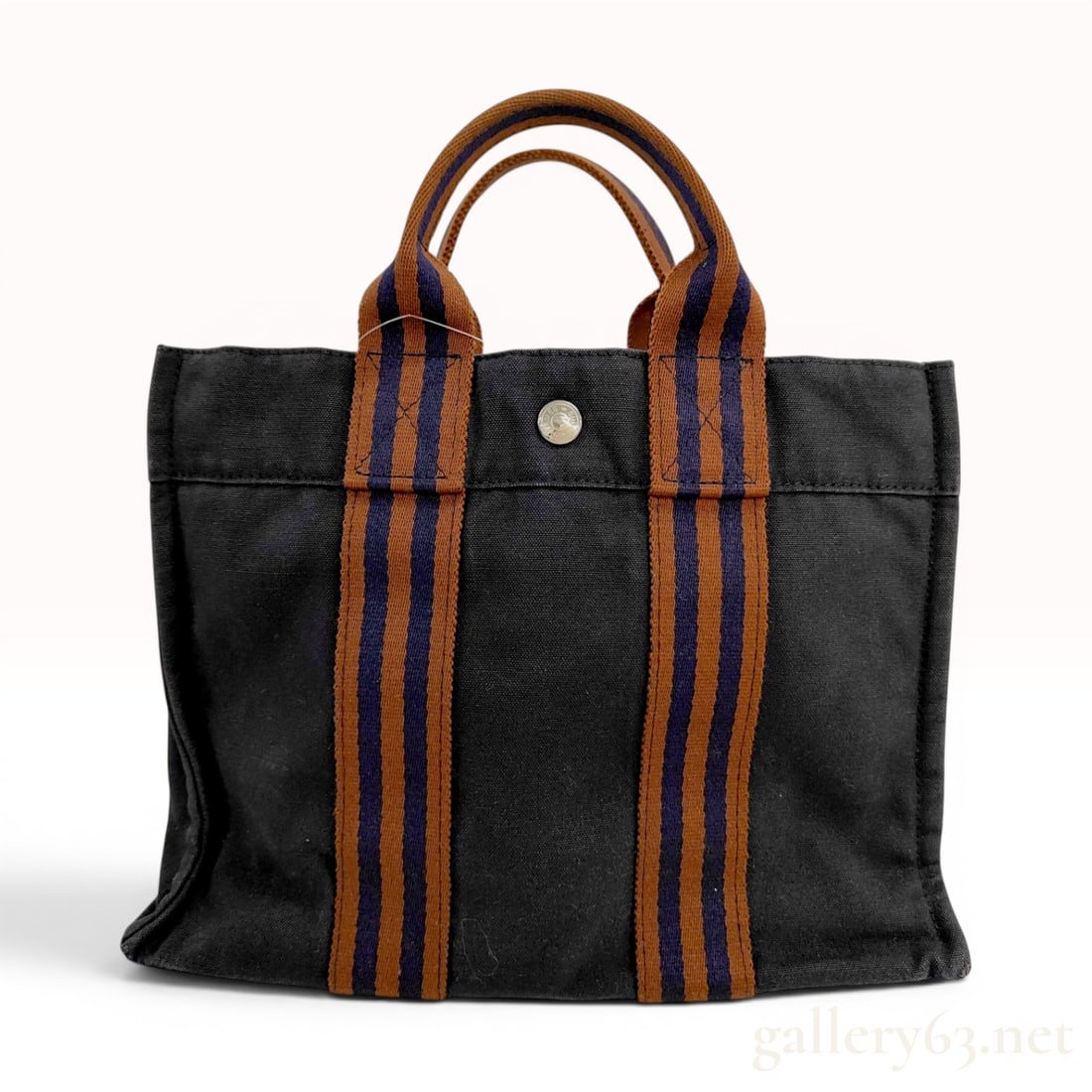 Hermes Navy Blue Canvas Fourre-Tout PM Tote Bag: This Hermes Fourre-Tout PM tote is constructed from a heavyweight navy blue cotton canvas body. The bag is accented by two vertical, multi-colored striped webbed handles in brown and navy blue that ex