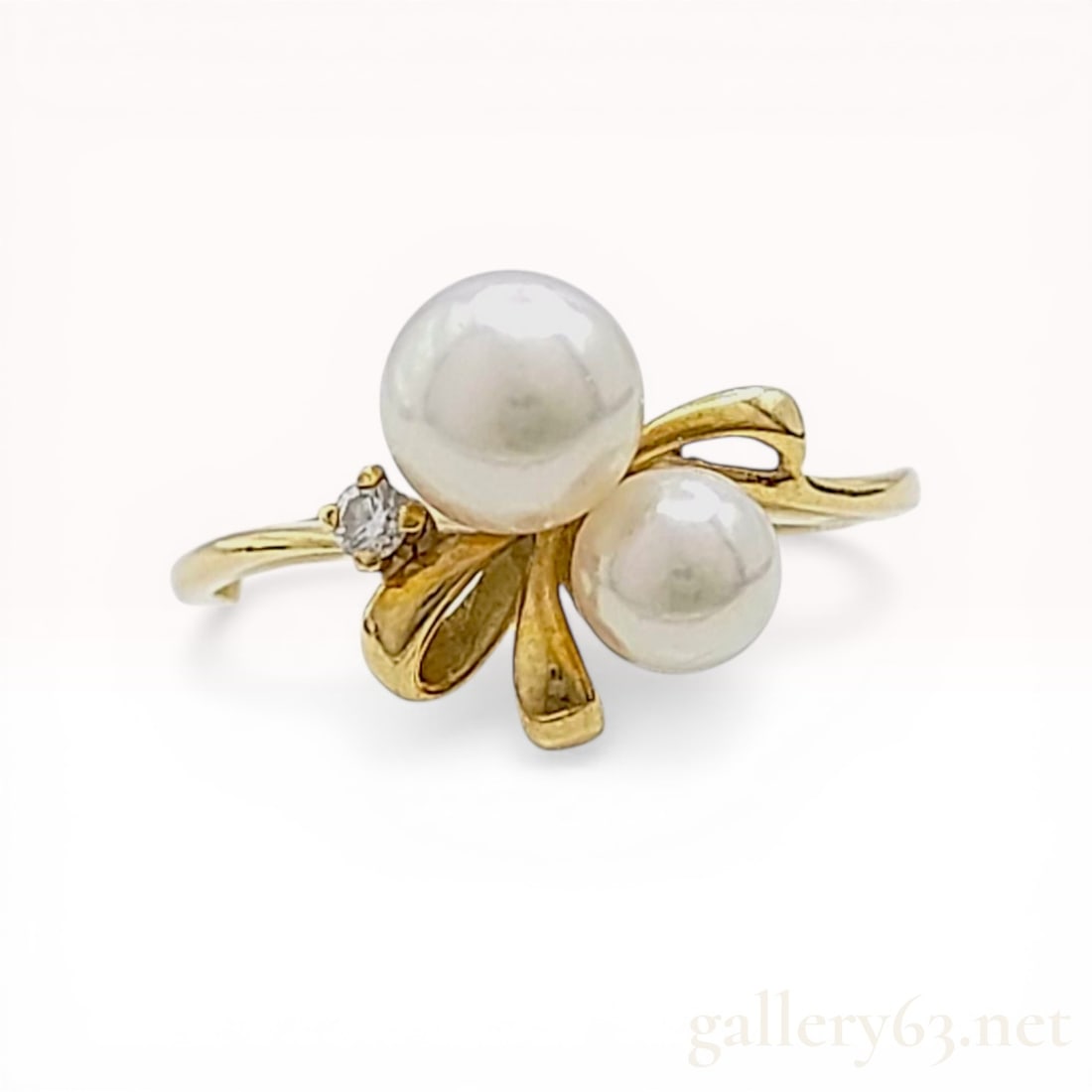 Mikimoto 18K Yellow Gold Cultured 4.5/5.6mm Pearl and Diamond Bypass Ring: Mikimoto bypass ring featuring two graduated white cultured pearls and a single round brilliant-cut diamond accent. The 18 karat yellow gold mounting is designed with a stylized ribbon motif and a fou