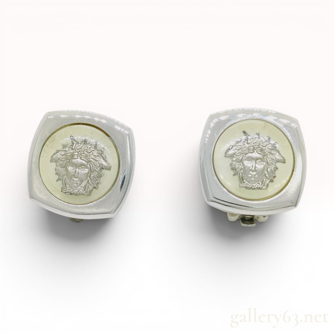 A Pair of Vintage Gianni Versace Silver-Toned Medusa Clip-On Earrings: A matched pair of vintage clip-on earrings by the Italian fashion house Gianni Versace. Each earring features a square silver-toned metal frame with rounded corners. The center of each frame contains 