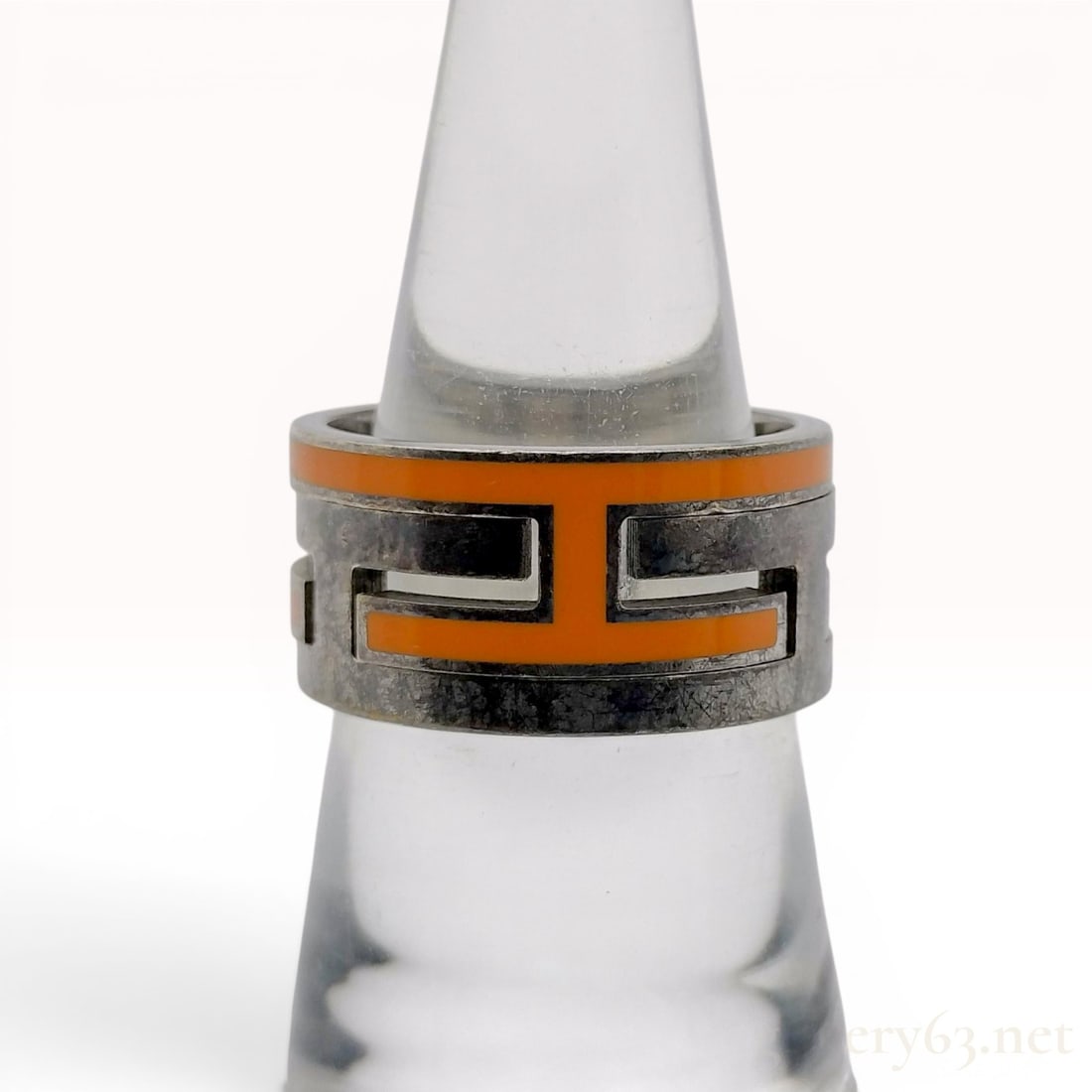 Hermes Sterling Silver and Orange Enamel Move H Ring with Box: A designer band ring by Hermes from the Move H collection. The wide sterling silver band features a repeating cutout geometric pattern forming stylized H motifs, accented with orange enamel. The inter