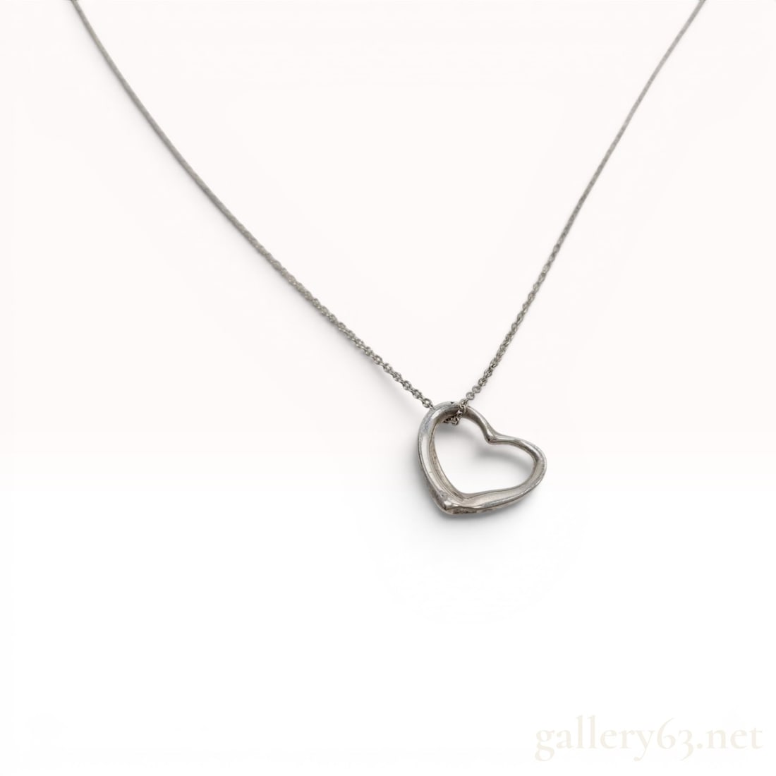 Tiffany and Co Elsa Peretti Sterling Silver Open Heart Pendant Necklace: A Tiffany and Co sterling silver necklace featuring an Elsa Peretti Open Heart pendant. The pendant consists of a fixed, stylized open heart suspended from a fine cable link chain. The piece is crafte