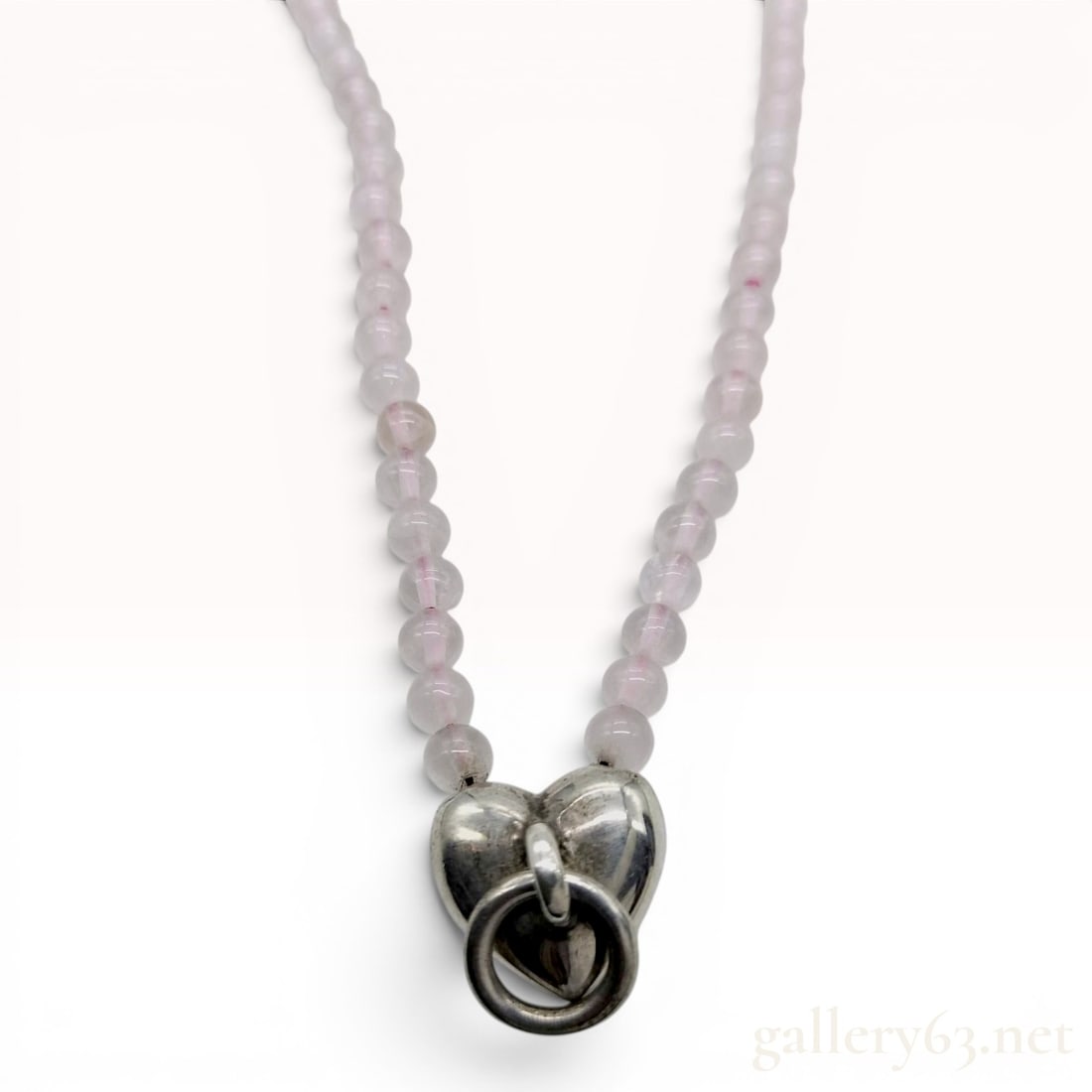 Tiffany and Co. Sterling Silver and Rose Quartz Beaded Heart Necklace: A Tiffany and Co. sterling silver and beaded necklace featuring a single strand of pale pink, translucent spherical beads, identified by consensus as rose quartz. The beads are hand-knotted on a coord