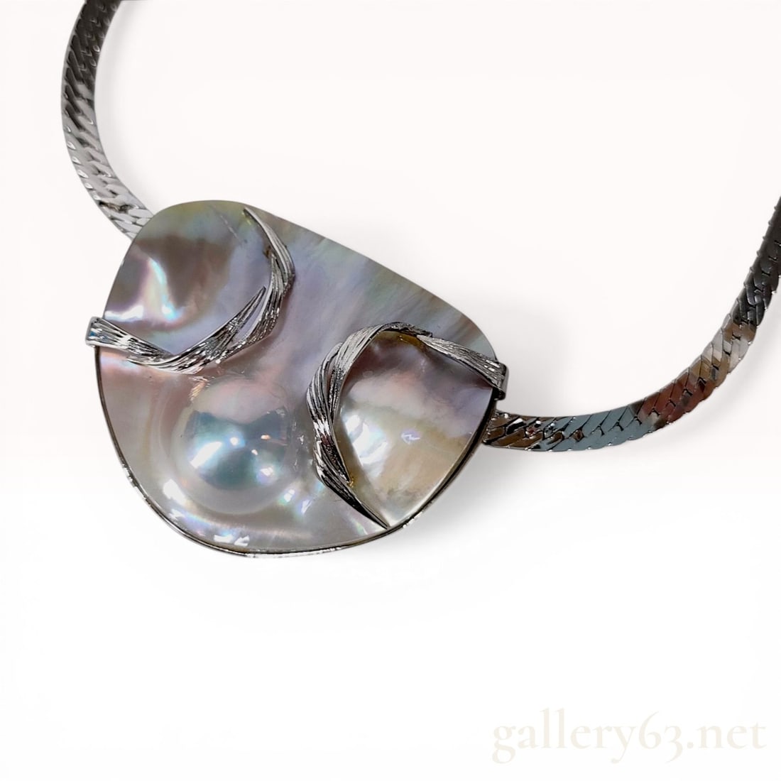 Sterling Silver and Large Blister Pearl Integrated Pendant Necklace: Contemporary sterling silver necklace featuring a large, asymmetrical freeform blister pearl accented with four textured silver foliate motifs. The iridescent mother-of-pearl displays pink and