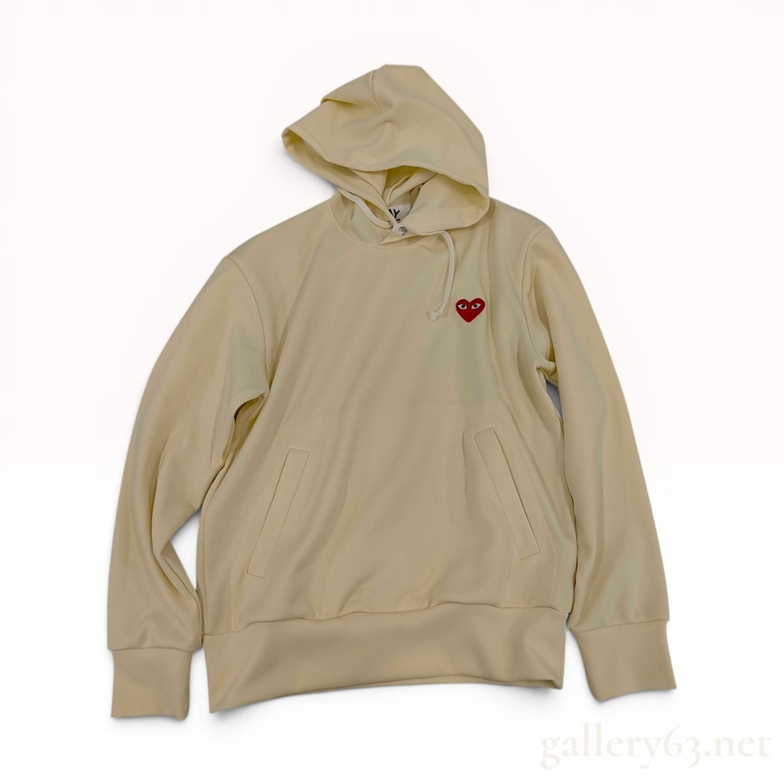 Comme des Garcons Play Red Heart Pullover Hoodie in Ivory Size Medium: A Comme des Garcons Play pullover hoodie in an ivory colorway. The garment is constructed from 100% polyester fabric and features the brand's signature red embroidered heart logo with eyes on the left