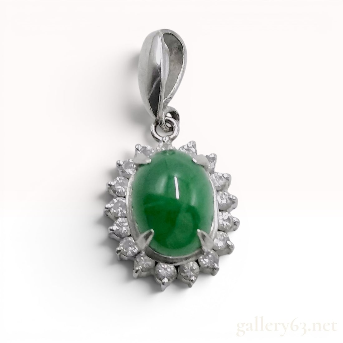 Platinum, Jadeite, and Diamond Halo Pendant: Platinum pendant featuring a central oval cabochon green jadeite stone within a tiered halo of eighteen round brilliant-cut diamonds. The piece is suspended from a polished tapered bail and exhibits