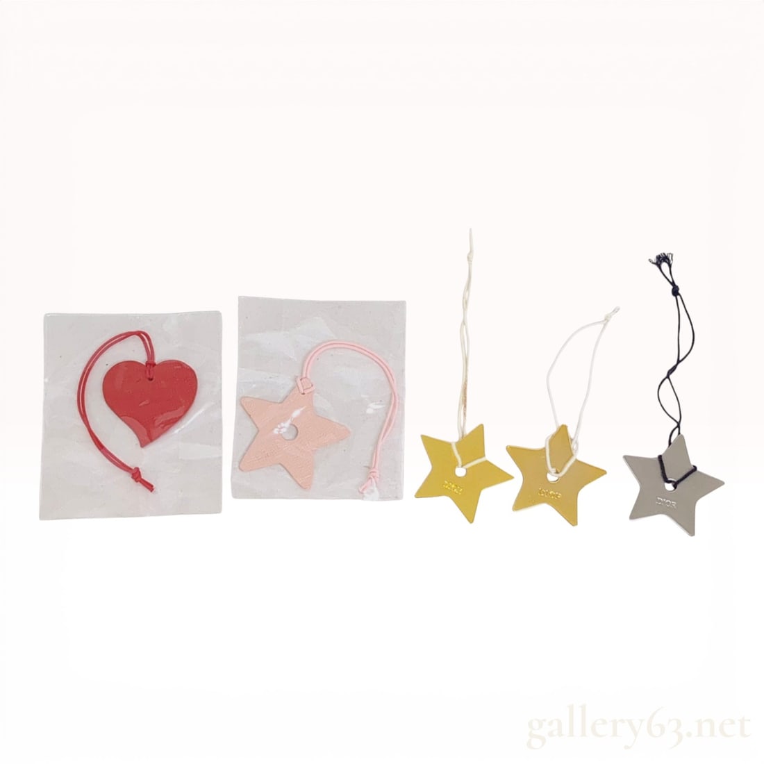 Set of Five Dior Star and Heart Decorative Bag Charms: A set of five designer decorative charms, featuring pieces from Dior. The collection includes two pebbled leather charms: one red heart-shaped charm and one light pink star-shaped charm with a central