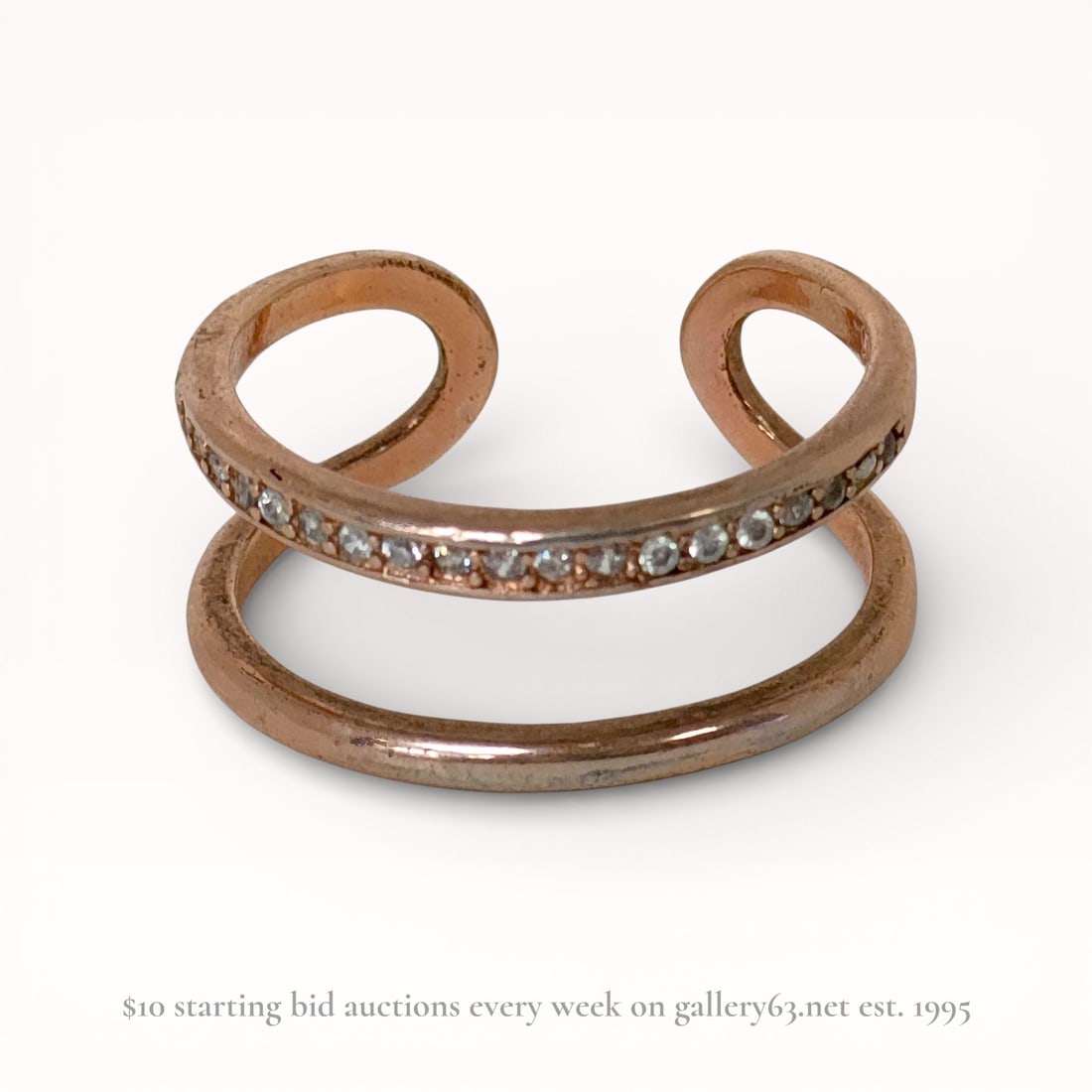 Rose Gold Plated Sterling Silver Open Double Band Ring: Contemporary open-front cuff ring featuring a double-band design in rose gold-tone plated sterling silver. One band is channel-set with a row of approximately 20 small round faceted colorless stones. 