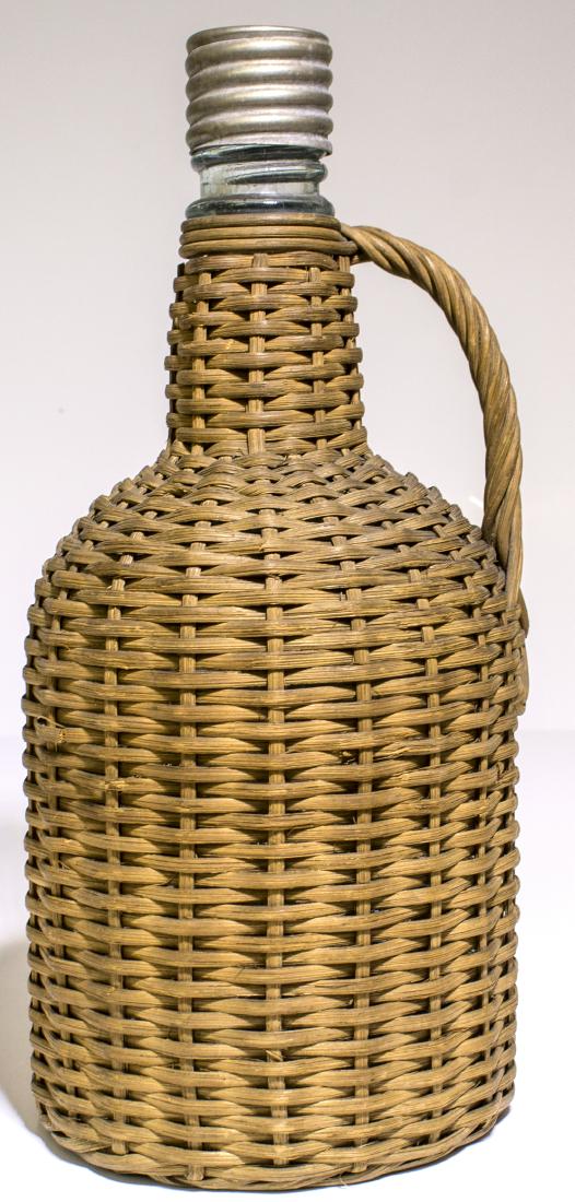 Ground Top Aqua Whiskey in Wicker (48529): Old Style , handled , wicker whiskey bottle. 9 1/2" Tall x 4 1/4" wide. Perfect condition , on the wicker. Also, very unusual to find a ground top and original cap , threaded bottle. Great table , or