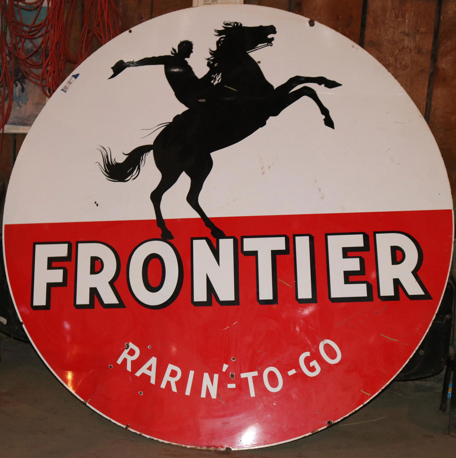 Frontier Gasoline "Rarin'-To-Go" Large (6 foot) Enamel: Very desirable 1958-59 Frontier "Rarin To Go" Gasoline single-sided porcelain service station sign. Condition: Excellent. Size 72" diameter. Shows Cowboy on Bucking Bronco. Red, White and Black. 1920s