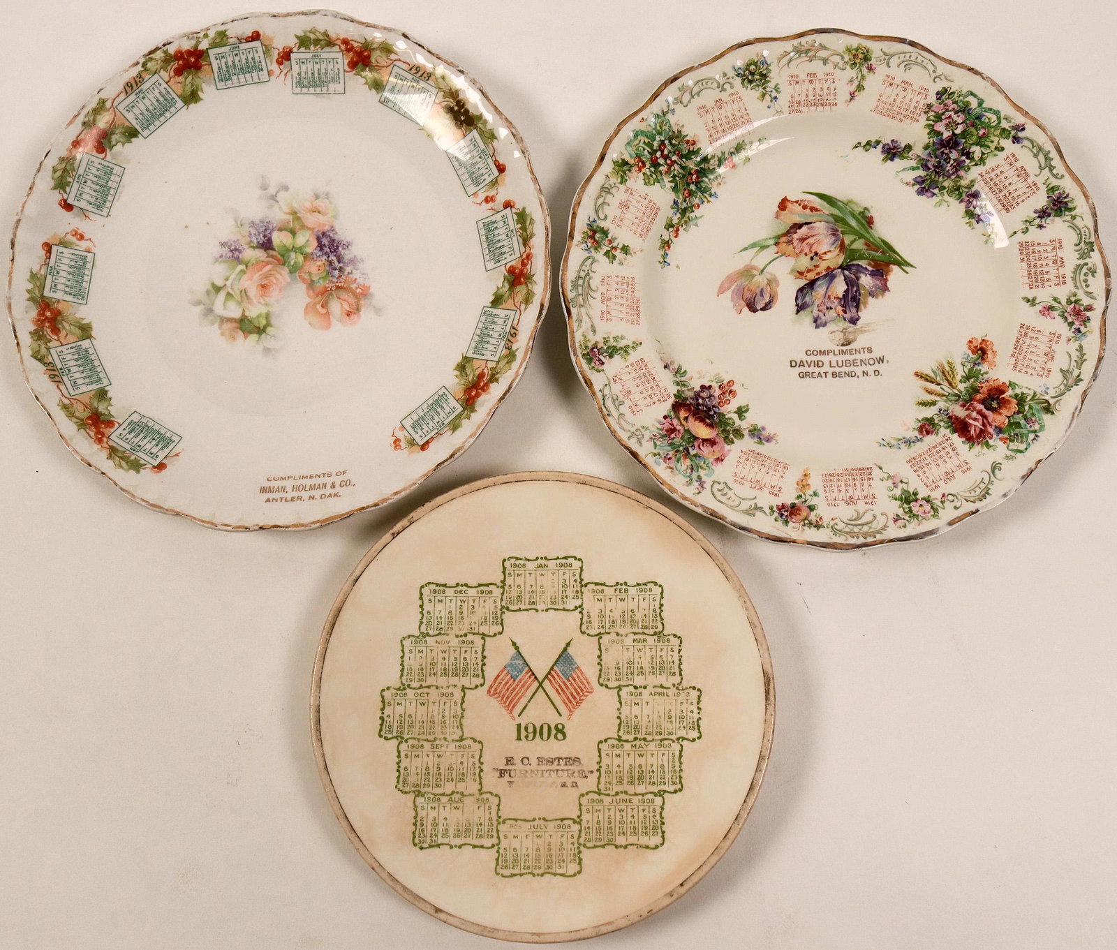North Dakota Souvenir Calendar Plates (3) (112609): Lot of 3. 1) 1908, E. O. Estes "Furniture." Wanpeton," N. D. Reverse: green print La Belle, China. Diameter: about 7.5 in. 2) 1913, Complements of Inman, Holman & Co. Antler, N. Oak. Reverse: brown pr