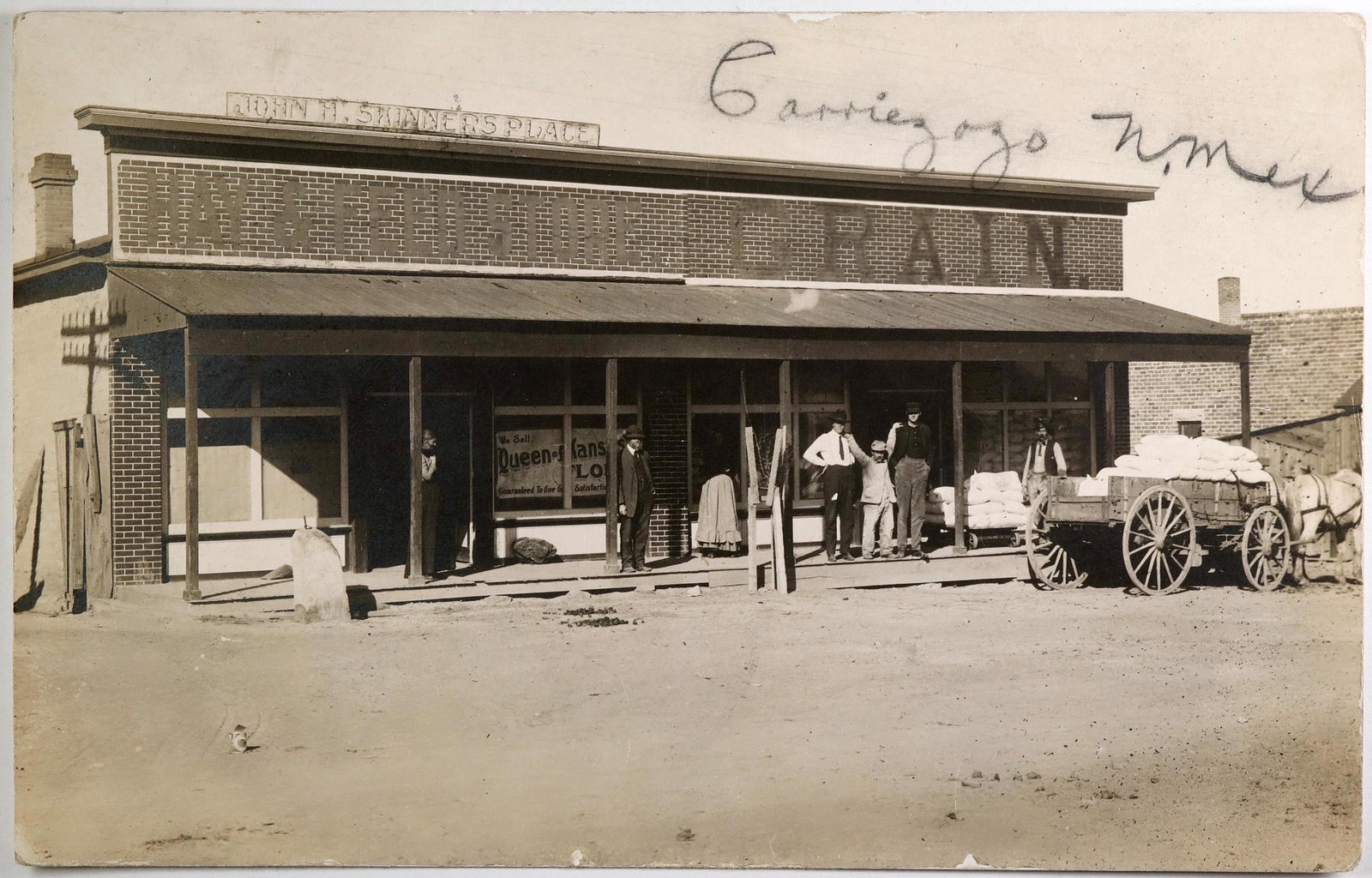 Carrizozo, New Mexico Postcard (1) (118470): This is a photographic postcard in a sepia tone. The John H. Skinner's Place Hay & Feed & Grain Store is prominently featured. In early 1900, the town provided the main railroad access for Lincoln Cou