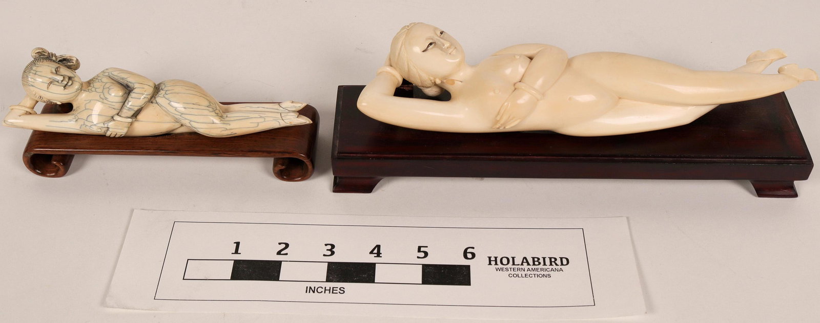 Carved Reclining Female Figures (108673): Two Asian female figures, carved from a synthetic material to look like ivory, reclining on wooden bases. The larger figure is 10 inches long and about 2-1/2 inches above the 1-inch tall wooden base. 