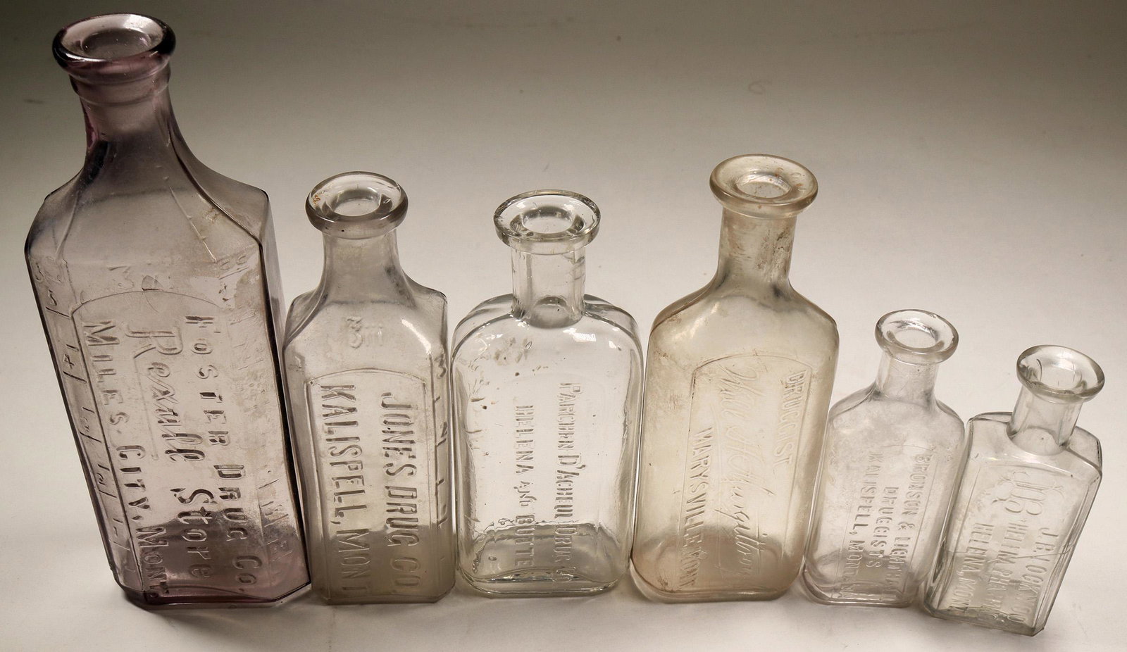 Montana Drug Bottle Collection (6) (125121): Six Different embossed drug bottles from Montana. Jones Drug, Kalispell 5"; Bronson & Lighthall, Kalispell 3 1/2"; Lockwood, Helena 3 3/8"; Parchen, Helena and Butter 4 7/8"; Foster Drug, Miles City 6