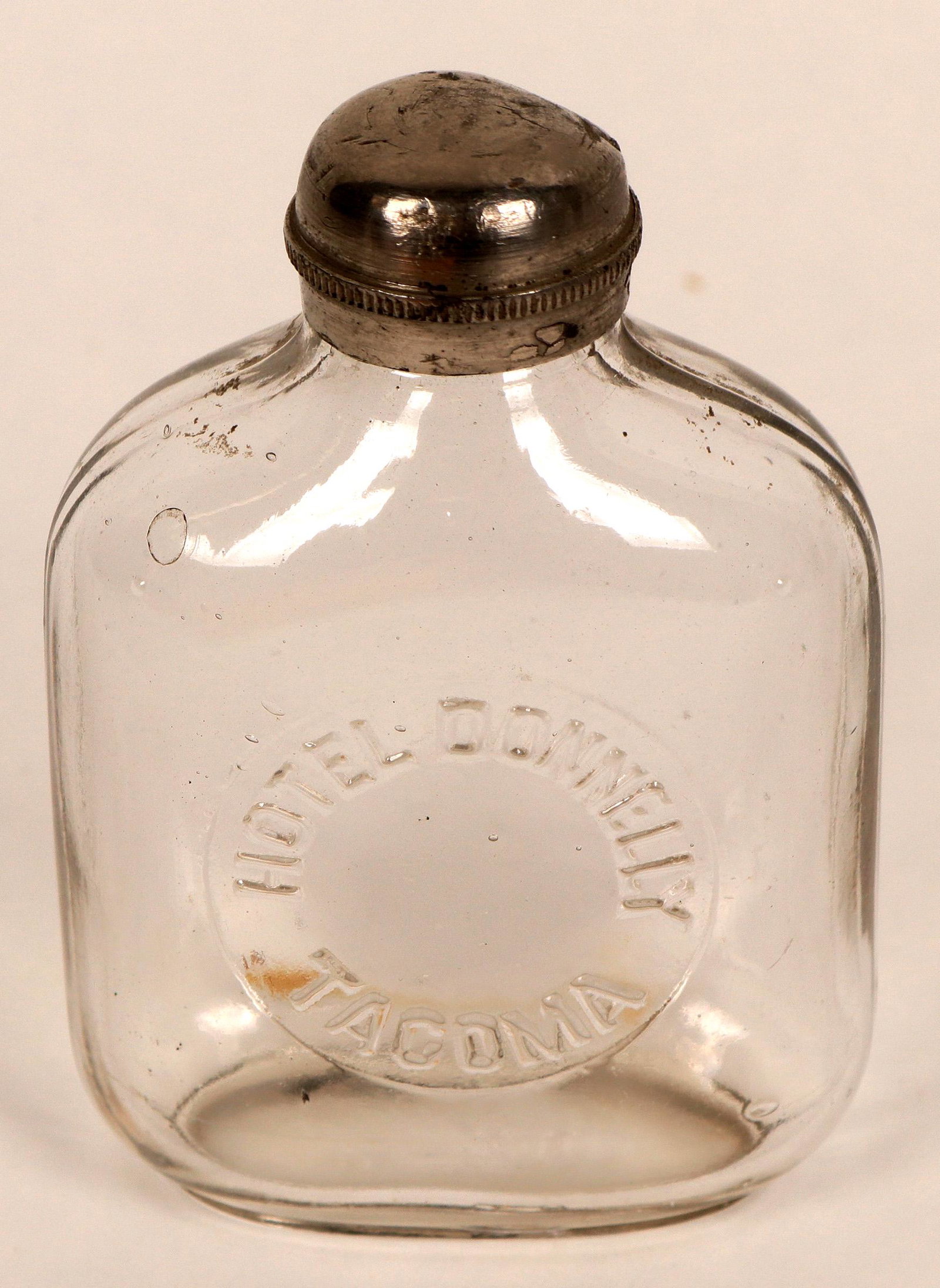 Washington Whiskey Flask (122122): Rare miniature hand blown sample size embossed whiskey flask w/original pewter cap. ..[x=#8221/] Hotel Donnelly Tacoma[x=#8220/] on front. The hotel was built around 1900-01. Excellent cond.Date: Coun