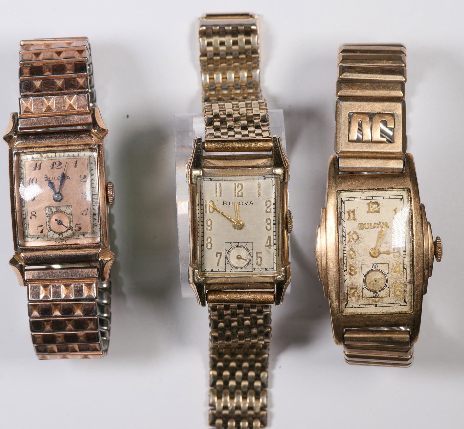 Three Bulova Wristwatches (124122): Lot of three: 1) Tank/semi curvex style, 22 x 30 mm, manual wind, circa 1943-48, case 14K rolled rose gold, Speidel band, ticks, needs cleaning. 2) Director, excellency series, circa 1947, manual wind