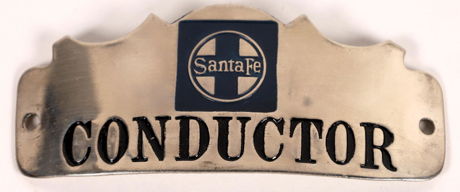 Santa Fe Railroad Scalloped Conductor Hat Badge: Conductor Hat Badge for the Santa Fe Railroad, scalloped design, likely silver-toned nickel with blue enamel logo and black enamel . Approx 3-1/4 x 2-1/2 inches.Date: Country (if not USA): State: City