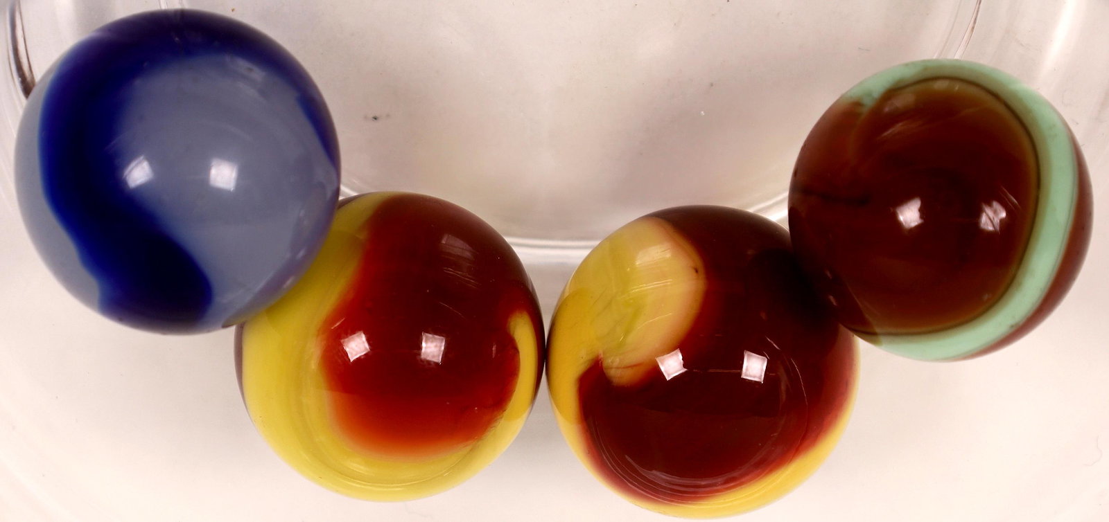 Akro Agate corkscrews (4) -shooters [127810]: Four Akro Agate shooters - 7/8 - 1". (2) Red and yellow - mint/mint minus, (1) Red and white - near mint, (1) Blue and translucent white - one tiny flea bite and a few surface scratches.Date: Country 