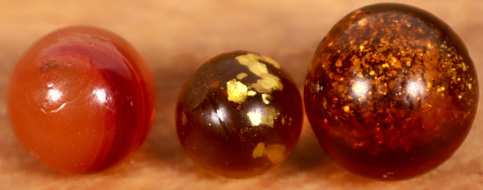 Butterscotch swirl, Mica marbles [127828]: 1. 3/4" Butterscotch swirl. Four small nicks on surface the rest is problem free. 2. 1" Amber mica with shrunken core. One small chip and several flea bites on surface. 3. 5/8" Amber mica with large m
