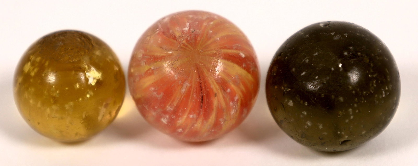 Mica marbles (2), Onionskin with mica (1) [127825]: 1. 1/2" Amber mica. Mint. 2. 5/8" Olive green mica. Mint. 3. 5/8" Yellow and red core with mica throughout. Mint minus with one tiny nick and a very small debris attachment at the time marble was made