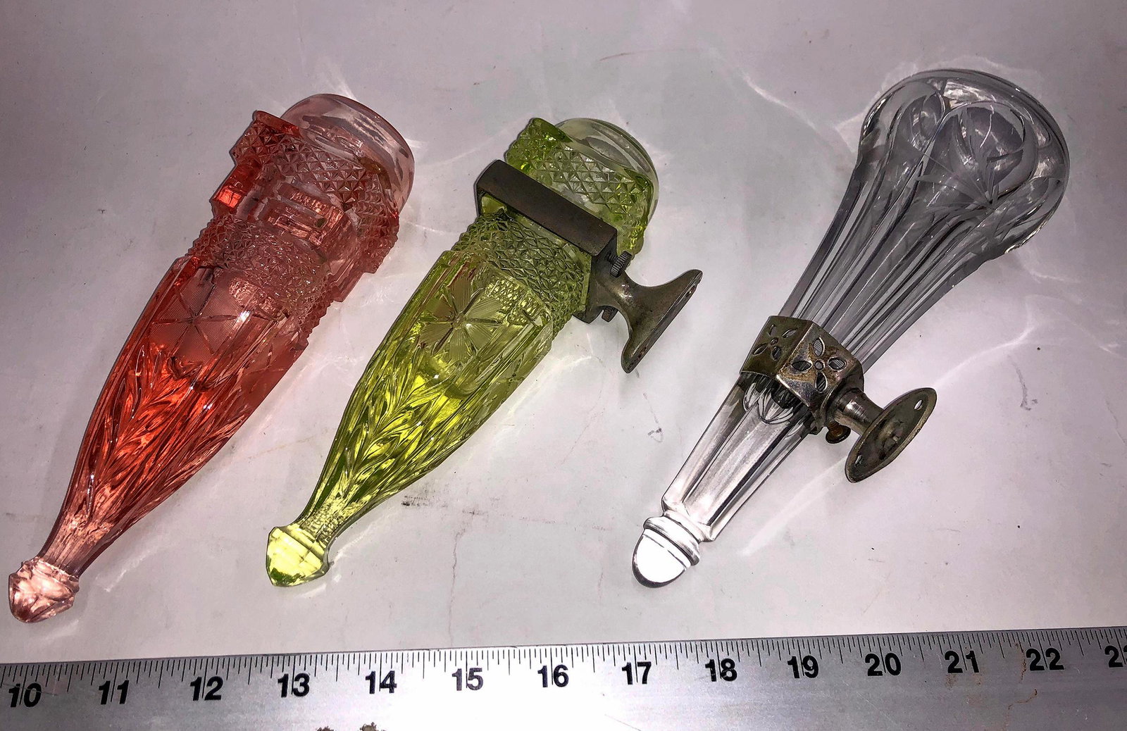 Three Different Wall or Vehicle Mount Pressed Glass: Citrine, rose, and clear. 7.5" long 2" square, only one original metal mount present. These could be considered wall pockets. The rose one had minor chips that are unnoticeable at first.Date: Country 