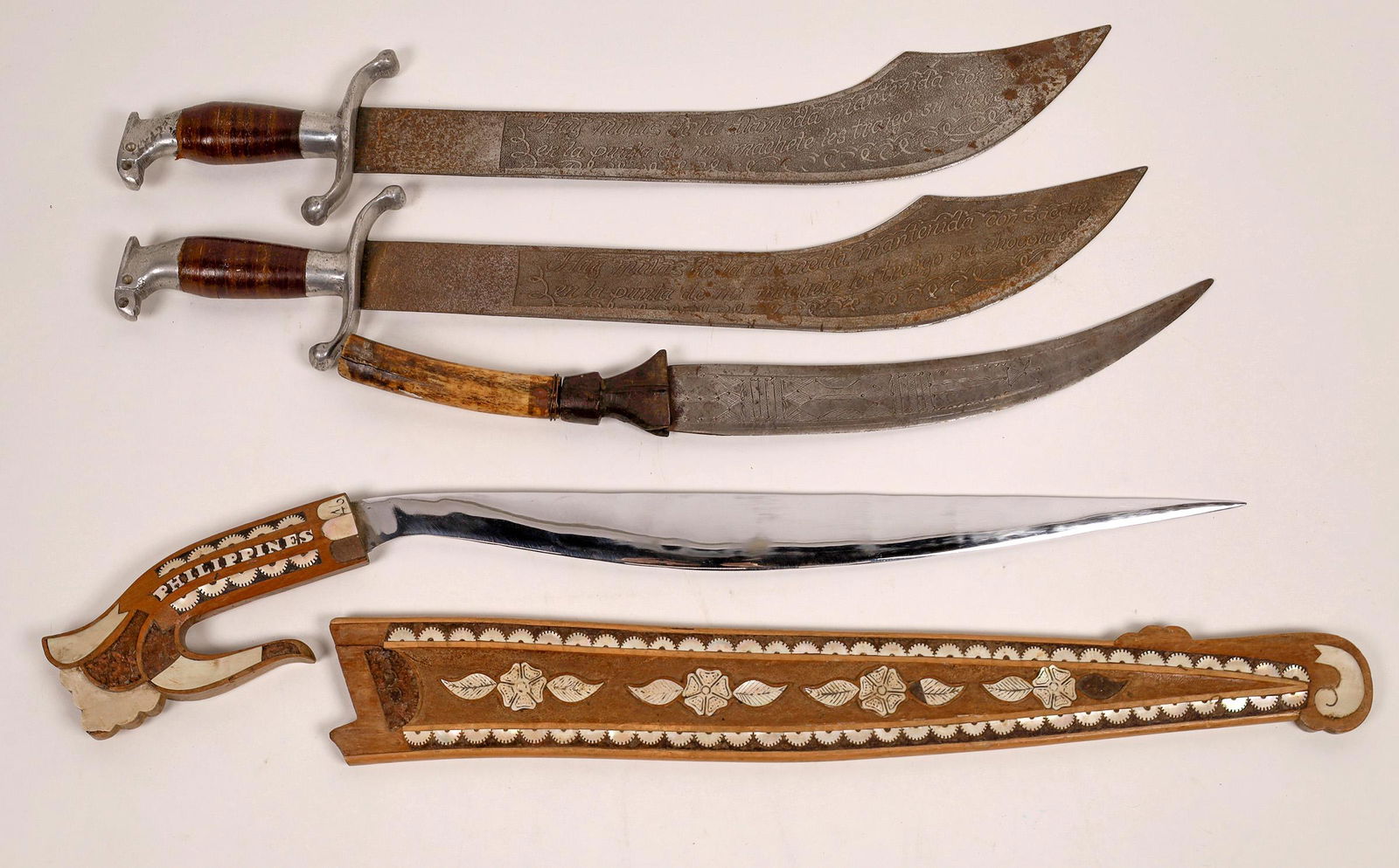 Large Knives and Machetes made in the Philippines: This is a lot of two large knives, and two machetes made in the Philippines. The knives are one with a bone grip handle, the other is larger and the sheath is decorated with abalone probably for the t