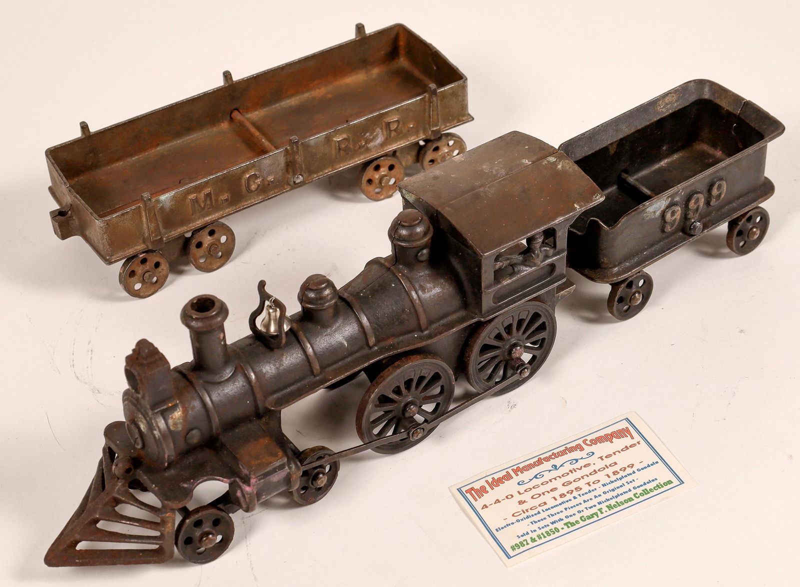 Cast Iron Locomotive and Gondola [133027]: Ideal Mfg Co. 4-4-0 with tender #999. Black in color. Gondola Car brown, marked M. C. R. R. Bell may have been replaced, but harp is original. Overall condition is excellent, paint shows little wear.