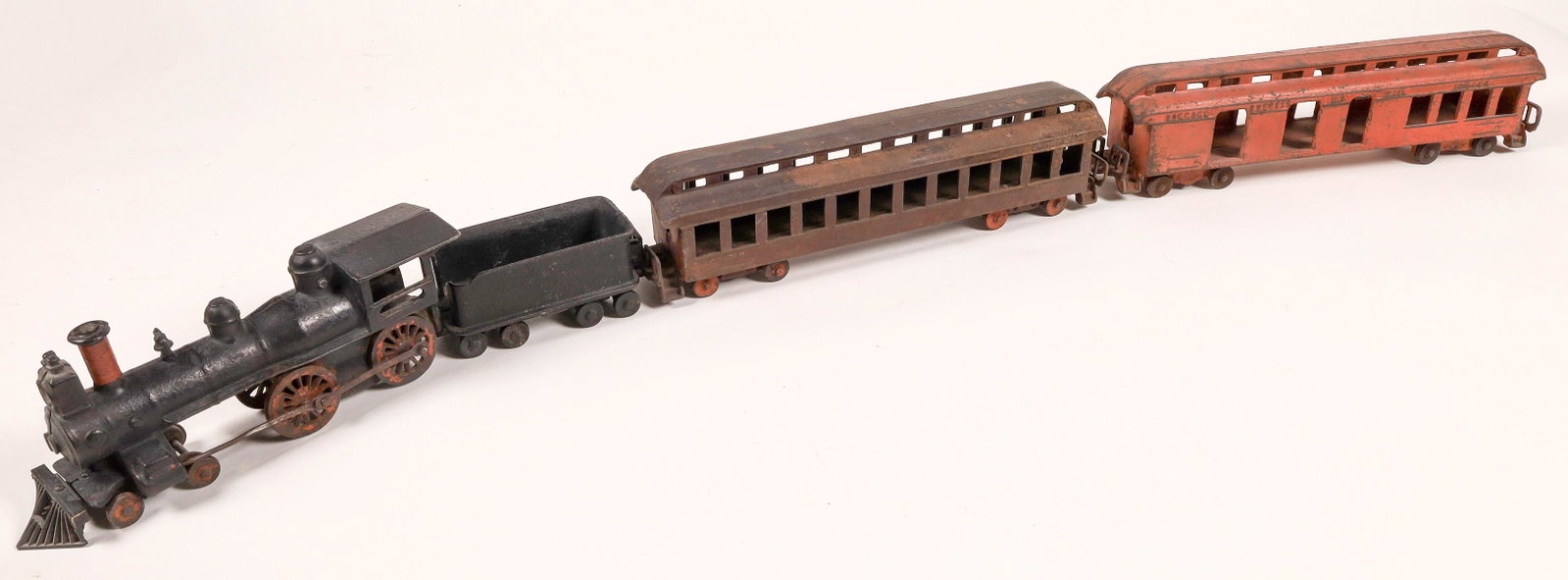 Cast Iron Locomotive, Tender, and 2 Cars [133039]: I. Junel Mfg. Co. 4-4-0 Black with red trim. Pilot has been replaced, not original. Tender with 8 wheels. First car is red Baggage Express U.S. Mail, marked as a Smoker. Paint shows wear. Second car i