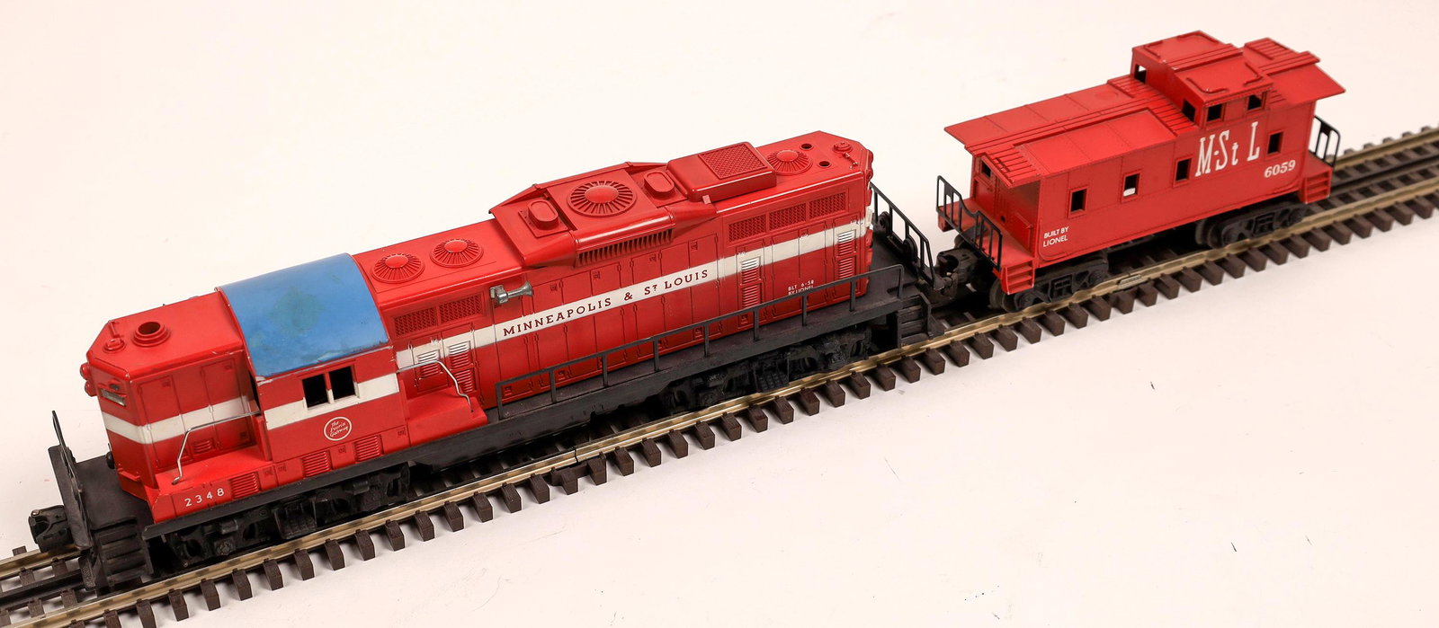 Lionel GP7 Diesel and Caboose [133157]: #2348 Minneapolis & St. Louis, Red, with white stripes, blue roof. Caboose #6059 M-STL on sides, red. C8. O-scale.Date: 1950s-60sCountry (if not USA): State: City: Provenance: Gary Nelson Railroad Col