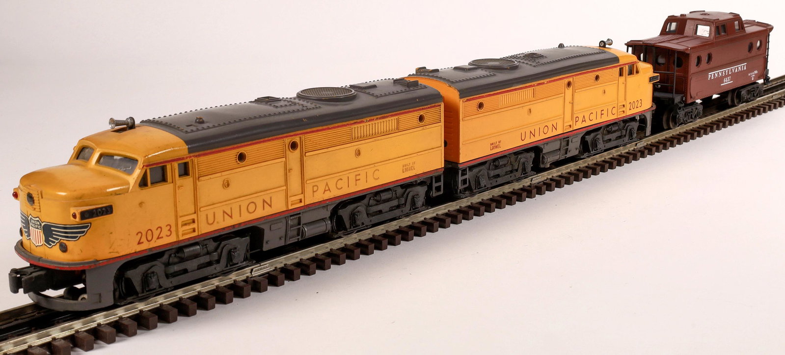 Lionel Union Pacific RR F3 Diesel AA Unit and Caboose: #2023 Loco, yellow with red stripe and gray roof. Company logo on nose, Union Pacific on sides. Caboose #6437 Pennsylvania, tuscan red. C7. Operational. O-scale.Date: 1950-51Country (if not USA): Stat