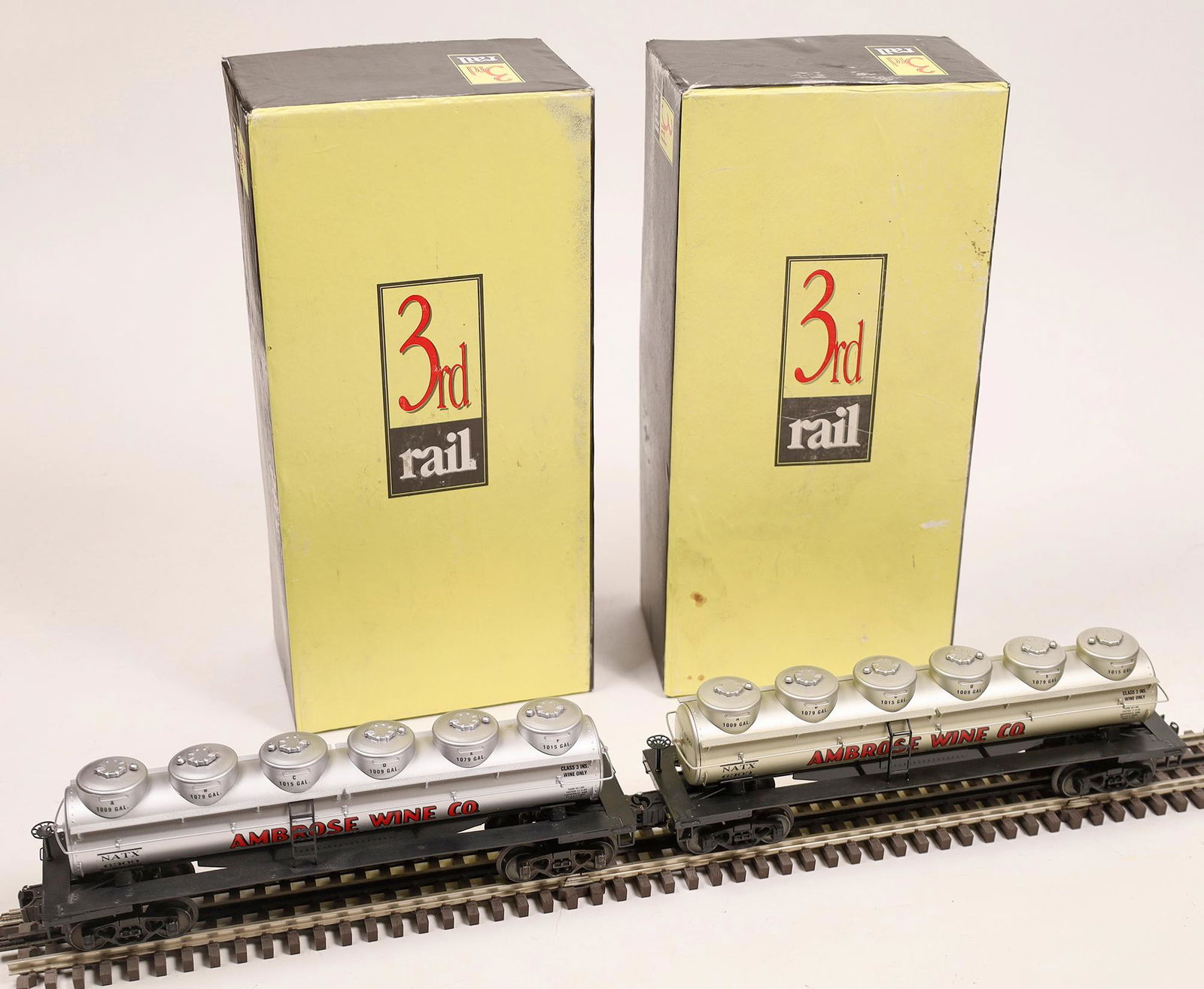 O Guage- Brass 6 Dome Wine Cars - 2 [133199]: Made by 3rd Rail, #6303 & #6309 in original boxes, 6 Dome wine cars, Ambrose Wine Company on sides. Brass cars. O-scale. C9Date: ModernCountry (if not USA): State: City: Provenance: Gary Nelson Railro