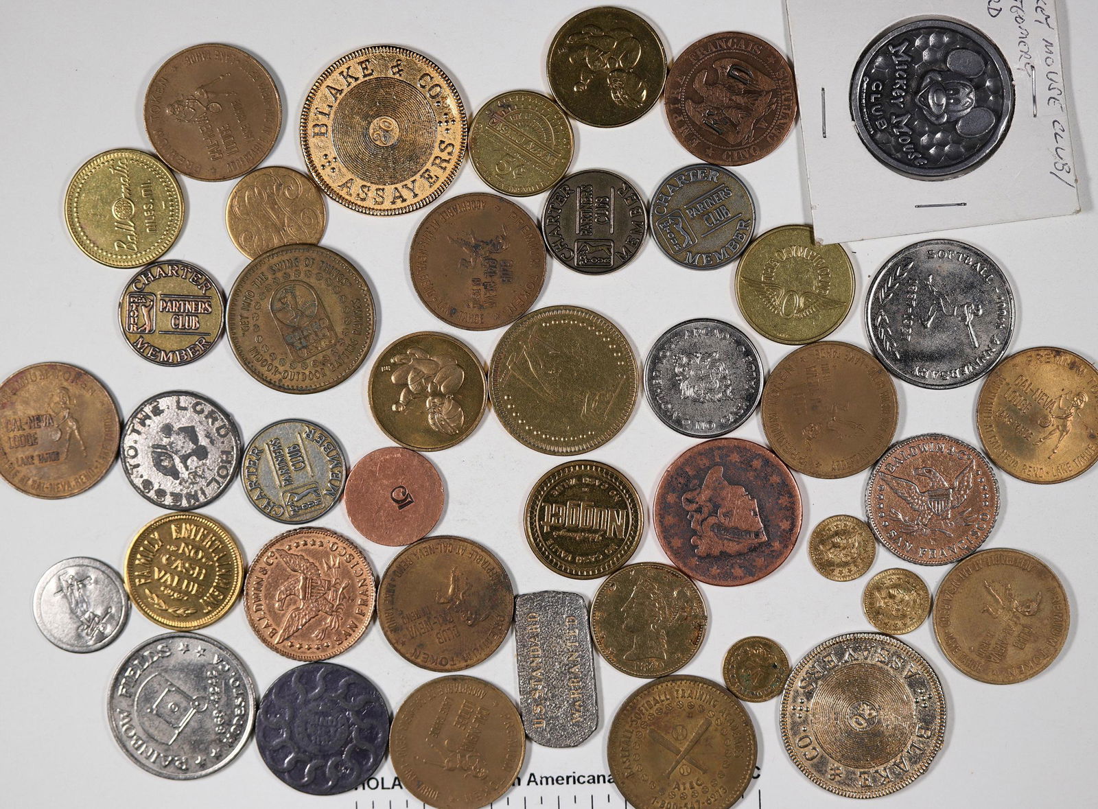 US Tokens (42) [129984]: Lot of 42 tokens from the US. Includes Mickey Mouse; 6 Nevada Casino arcade pieces; 7 faux pioneer coins; 3 cal gold tokens; large cent; 1849 cal counts; gold love token; 9 golf tokens; 8 Cal Neva 50x