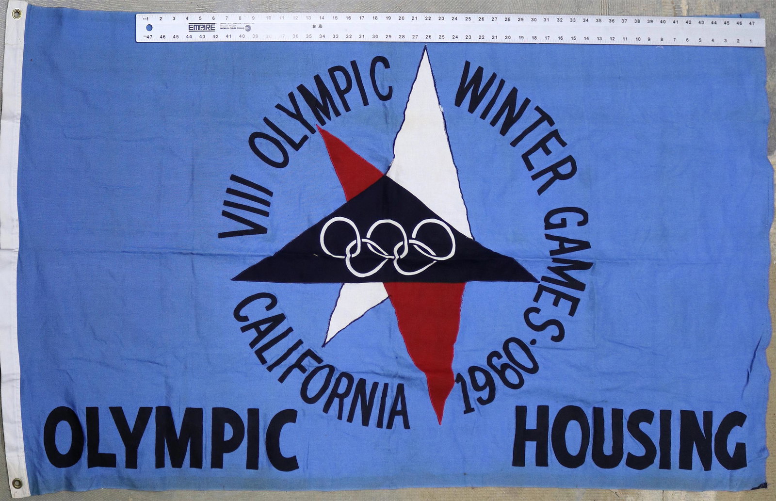 Olympic Flag from 1960 [131381]: Measures 5 feet long x 31" across. Hand constructed. "VIII Olympic Winter Games / California 1960 / Olympic Housing". Blue, Red, white and black. A unique flag made for housing at the Squaw Valley Oly