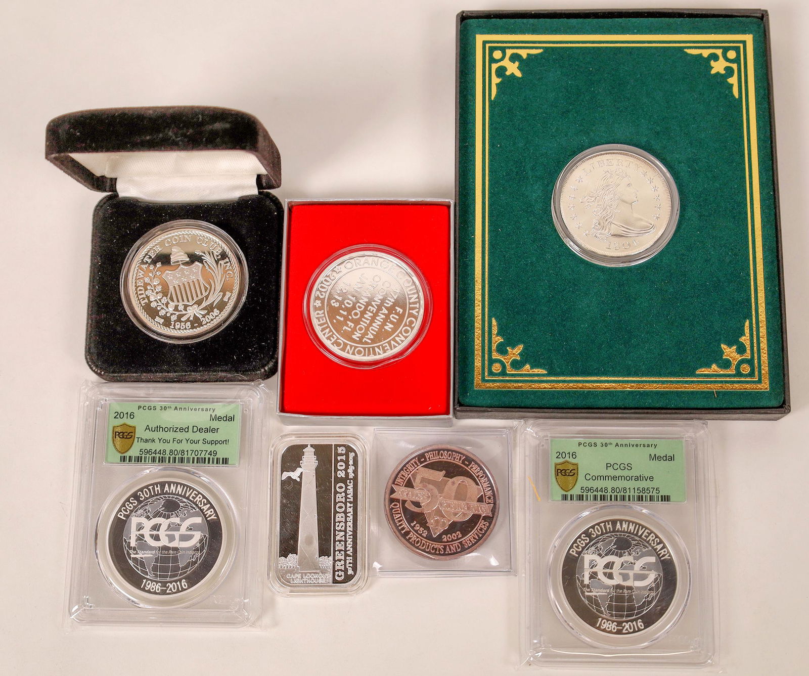 Silver Commemoratives of Coin Shows [129152]: Lot of seven silver pieces issued by coin shows: 2016 30th Anniversary of PCGS (2); 1804 silver dollar COPY in original box from Gallery Mint Museum; 2006 Tidewater Coin Club; 2015 Greensboro; 2002 Or