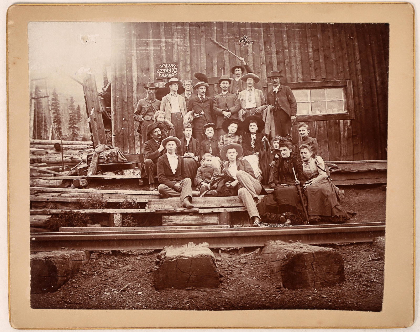 Pacific Express Office Family Photograph [122514]: This photograph features a large family posing outside of a dilapidated Pacific Express Company Office. The Pacific Express Company dealt with regional private mail and packages, operating primarily w