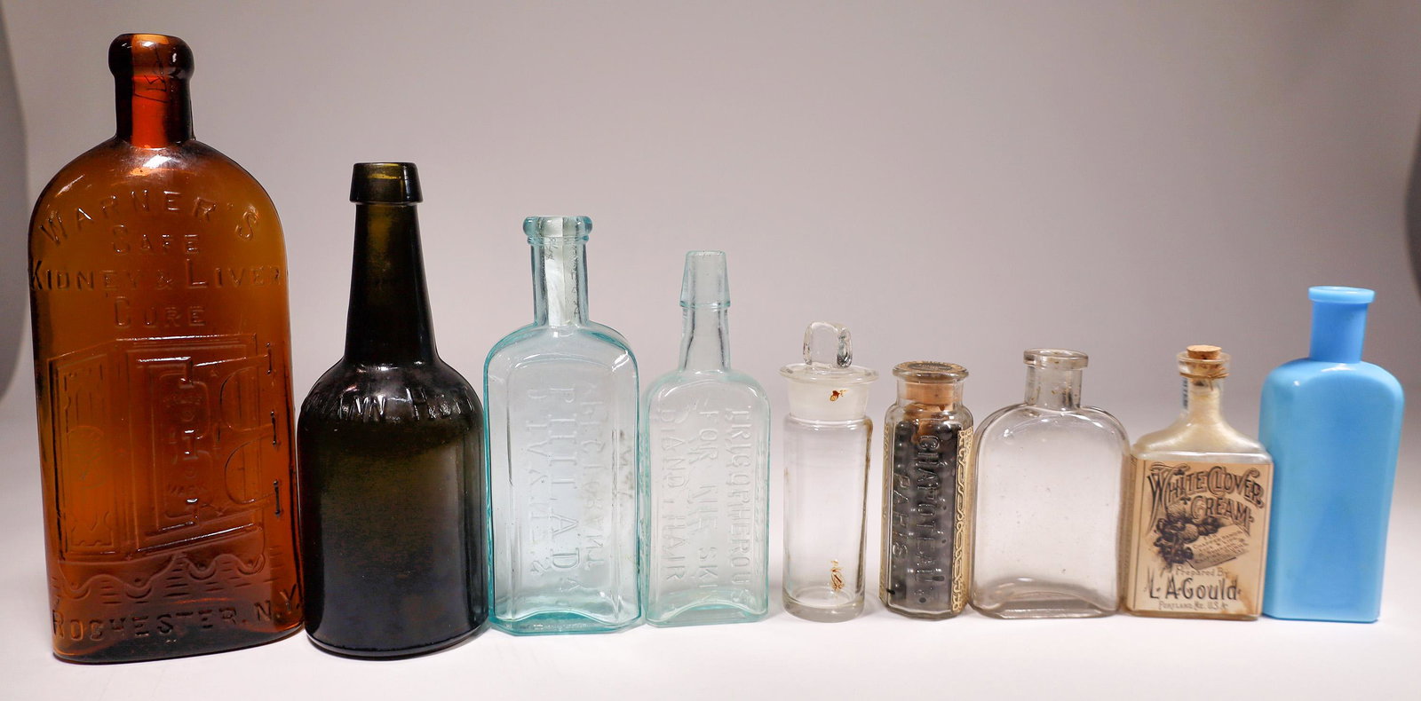 Antique Bottle Collection (24) [132274]: Nice collection of a wide variety of antique bottles in shape, size and genre. Includes a Warner's Safe Cure, many aqua embossed medicines, two original paper labeled medical bottles with original con