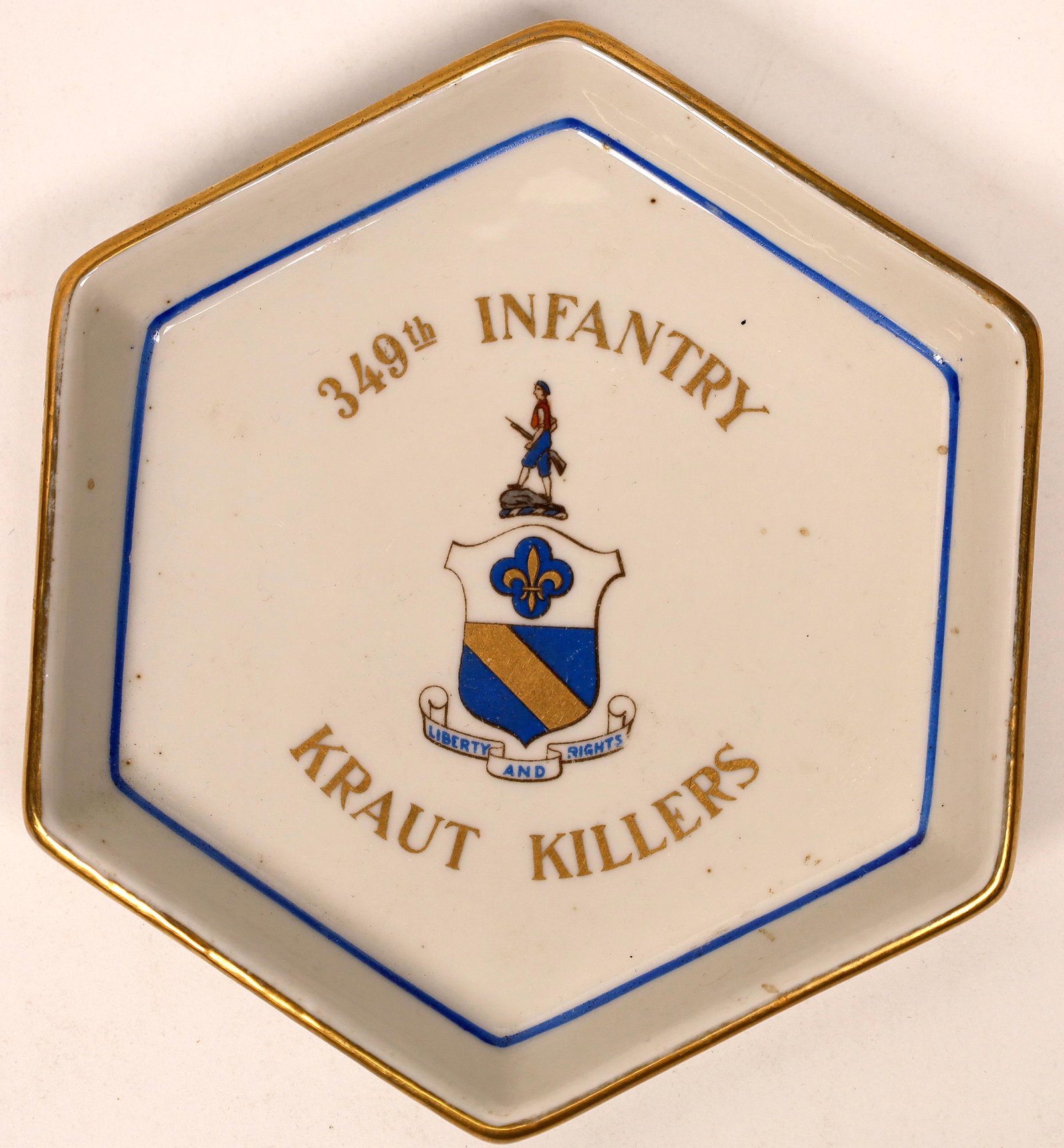 World War II Trinket Dish: 349th Infantry, the "Kraut: Hexagonal porcelain dish made by Richard Ginori. Front has blue and gold lettering, along with logo: 349th Infantry / Liberty and Rights / Kraut Killers. 5.5 x 5" Back is stamped Richard Ginori, NC. L