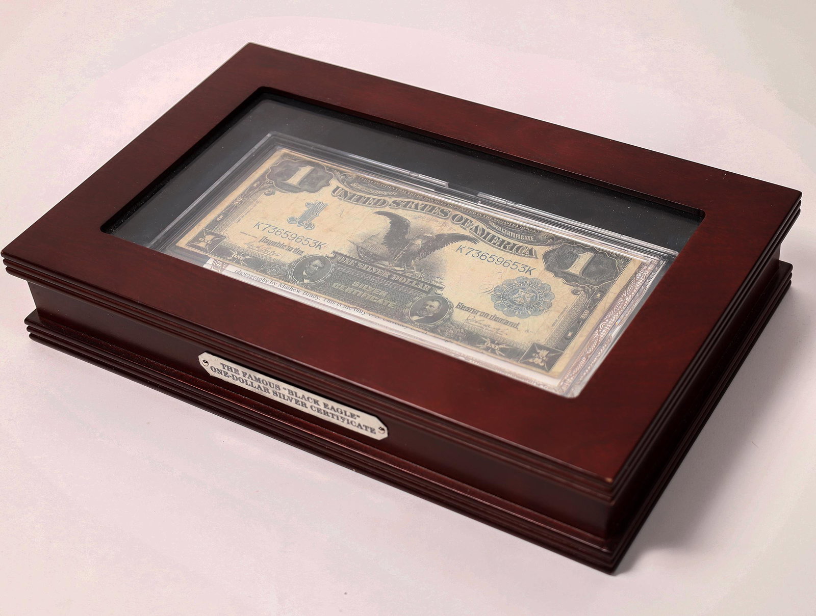 Black Eagle $1 Silver Certificate [153534]: Wooden box (11 x 7 x 2 inches) with glass top featuring a Series of 1899 Black Eagle one dollar silver certificate. The bill is VG condition, with a center crease, housed in hard plastic with a story
