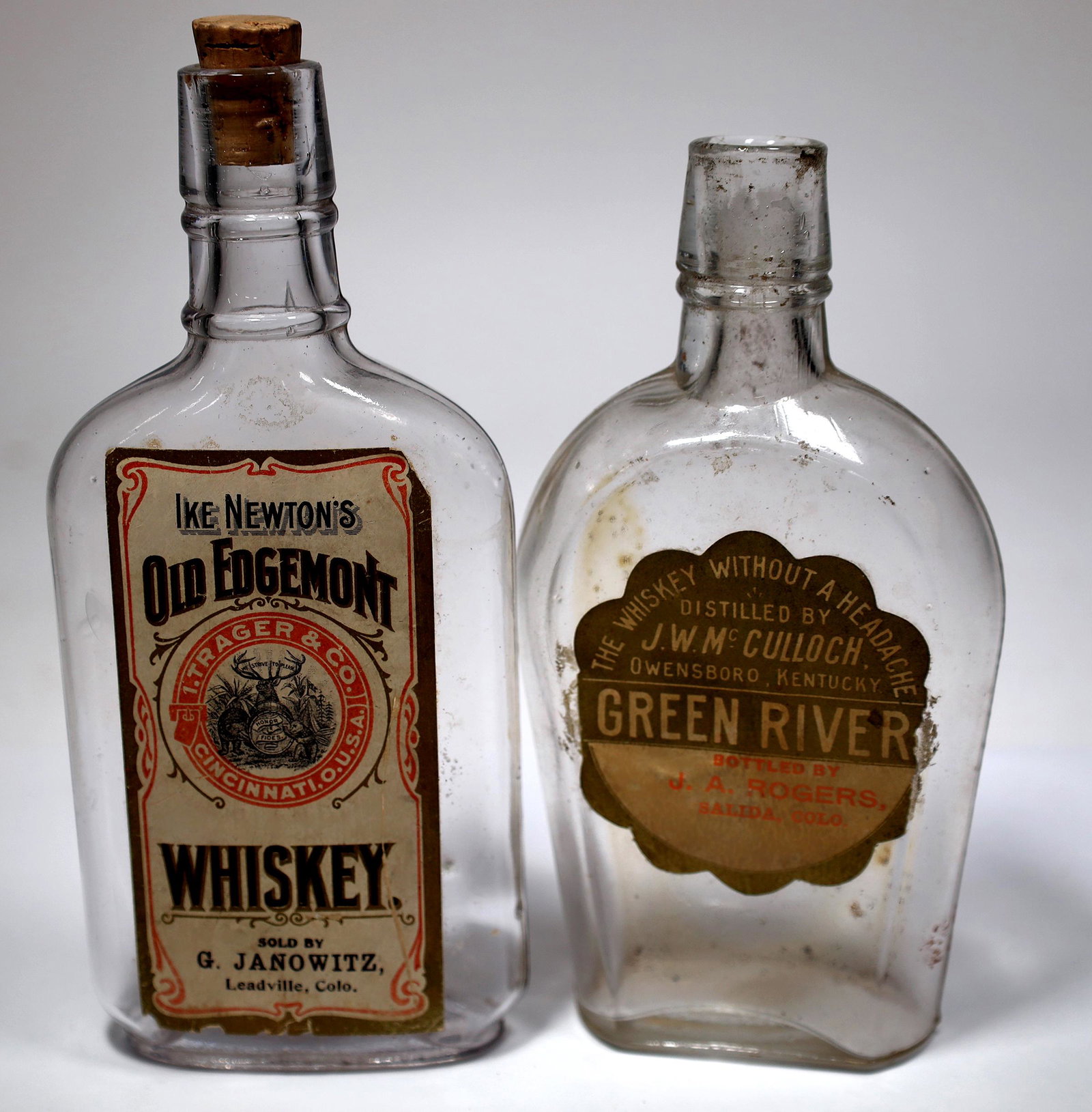 Leadville Region Paper Label Flasks [153765]: Lot of 2 different. 1) Ike Newton's Old Edgemont Whiskey, Sold by G. Janowitz, Leadville. Pictorial label with some chips around the edges. Bottle is 6 5/8" with cork. 2) Green River whiskey, Bottled