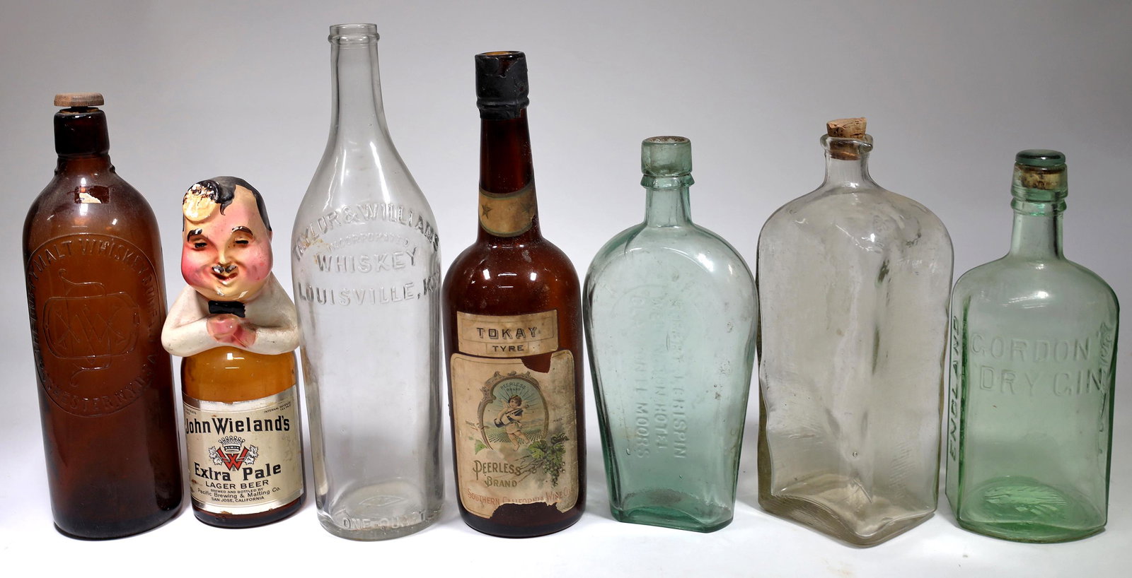 Wine, Beer and Liquor Bottles, 7 [155016]: John Wielands Extra Pale Leger Beer with half body top, amber Duffy Malt Whiskey, Coffin lime Robert J. Crispin/Wellington Hotel, clear fifth Taylor & Williams Whiskey, Gordon's Dry Gin with molding d