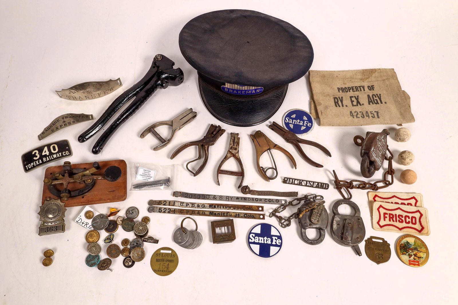 Railroad Collectibles and Ephemera [160692]: A T & S F Railway lock and key, Ouray Stage and Bus Company brass tag, Missouri Pacific Lines, Maintenance Way lock and key with chain, assorted buttons, badges and pins, hand operated stamper(cannot