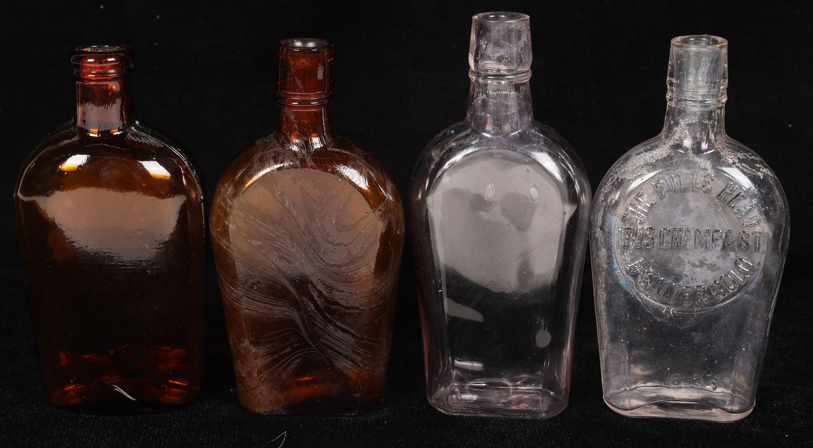 Bulls Head Shoefly Half Pint Whiskey Bottle [173587]: Clear shoefly half pint. The Bulls Head/1705 Champa St./Denver, Colo. 6". Lip ding, no apparent chips or cracks. 3 unembossed half pint flasks of a similar age, see photo. Denver Colorado