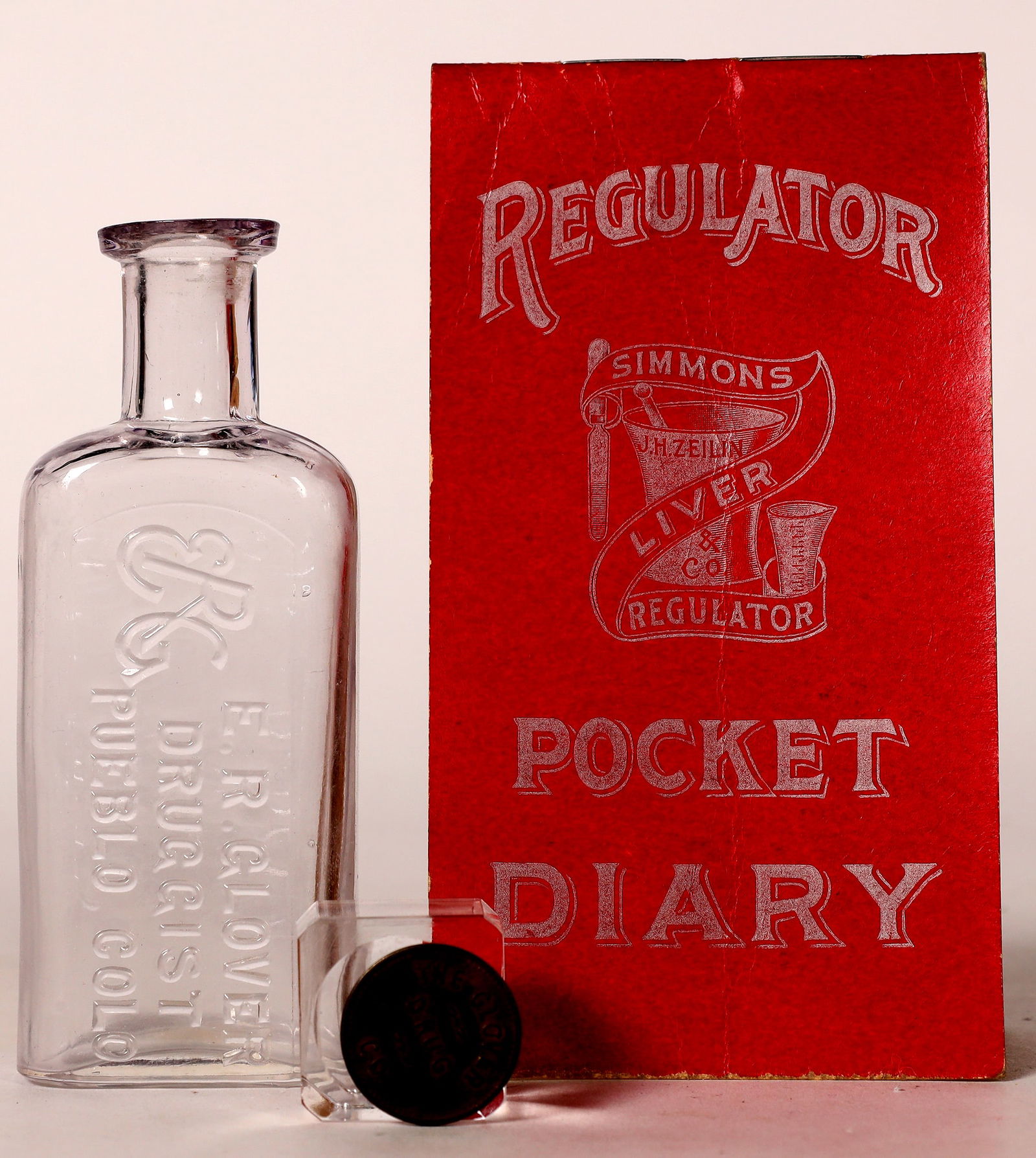 E.R. Glover, Pueblo, Colo. Drugstore Bottle, Token, Pocket Diary [174922]: E.R. Glover Drugstore Bottle, E.R. Glover/ Druggist/ Pueblo, Colo., mint, no apparent chips or cracks, 4.25"-R-4; Token, The Glover/ Drug/ Co., 201 S. Union// Pueblo, brass, round, 13/16"; and Pocket