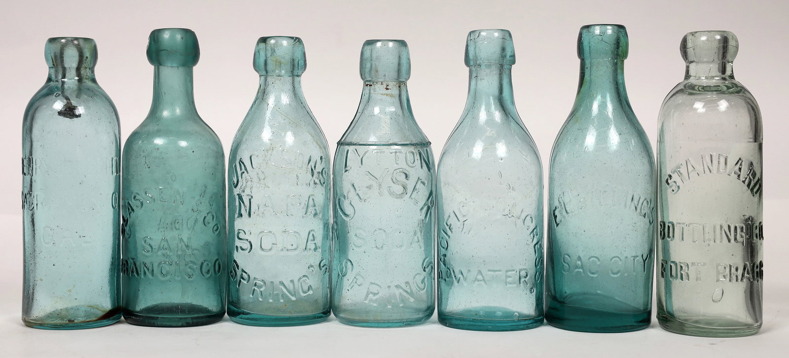 Sacto-Napa Area Blob & Hutch Soda Bottles (7) [178707]: A collection of seven aqua & green Sacramento-Napa area blob top Hutchinson embossed soda bottles. Most have imperfections of some kind. Included are: Standard/Bottling Co./Fort Bragg (on front), ligh