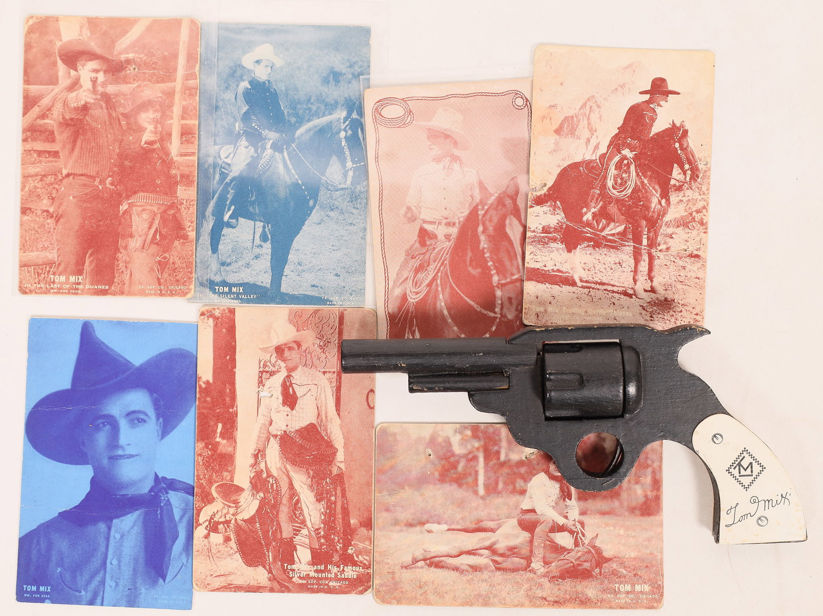 Tom Mix Collection [178893]: 7 thick Tom Mix postcards. Some have hanging holes. Wood revolver in original box with hanging end flap and 1 small flap missing, 8.5". Robert Coelln Collection