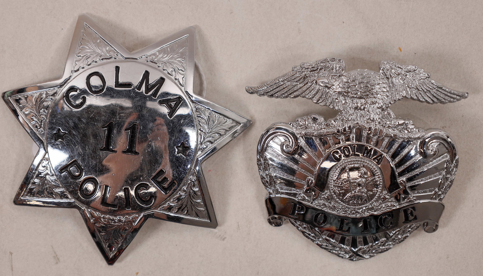 Colma Police Badges [179041]: Two metal badges from the Colma Police department. 7 pointed star: Colma / 11 / Police; pinback. Eagle holding the shield: Colma / Police. Colma California Salvatore Falcone Collection