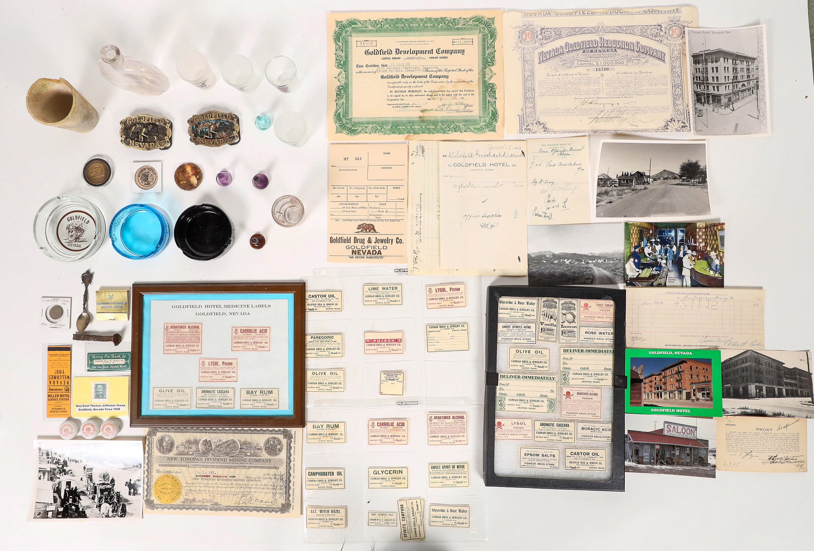 Goldfield, Nevada Collectibles & Ephemera [195335]: Large and diverse group of Goldfield collectibles. 50+ items. Includes: Goldfield Hotel prescription labels, five shot glasses, three ash trays, historical photo reprints, five mining stock certificat