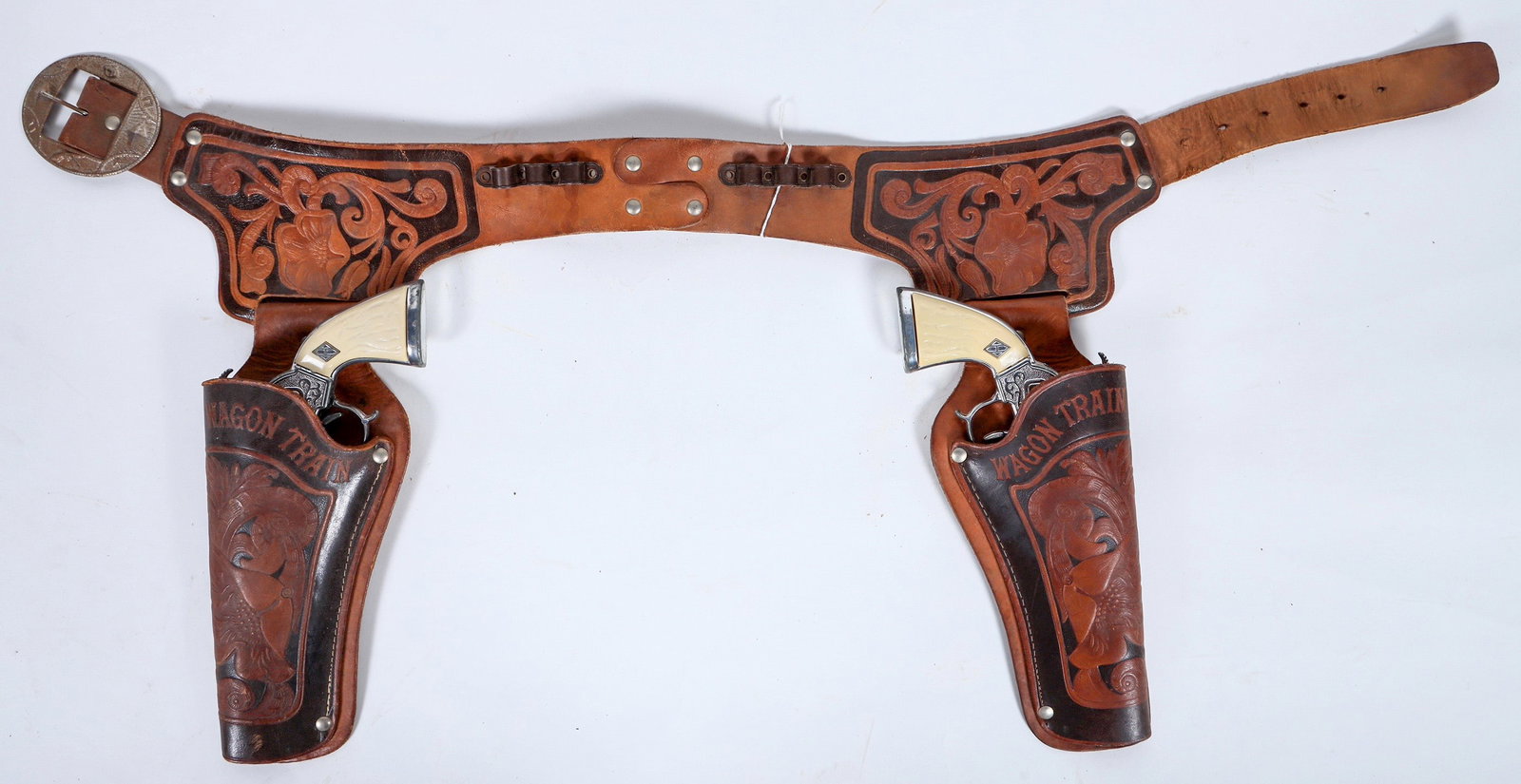 Hubley Wagon Trail Cap Gun and Holster Set [196328]: This cap gun and holster set made by Hubley has two "Wagon Train" Colt cap pistol revolvers with the original two tone leather holsters and gun belt. The guns come with imitation ivory grips and the b